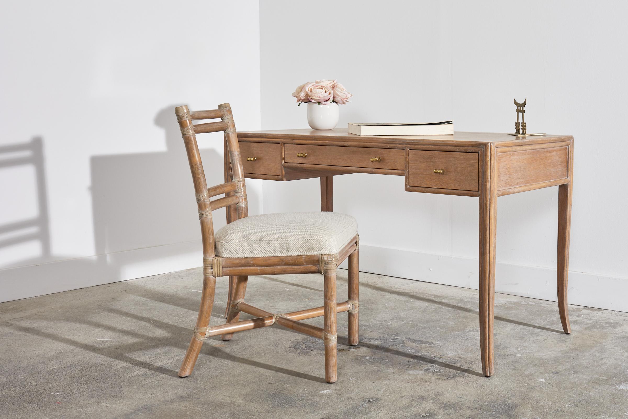 Elegant organic modern writing table or desk designed by Elinor McGuire in the California coastal style. The desk features an oak frame with split rattan accents on the borders giving the design a reeded look. The oak and rattan has a subtle cerused