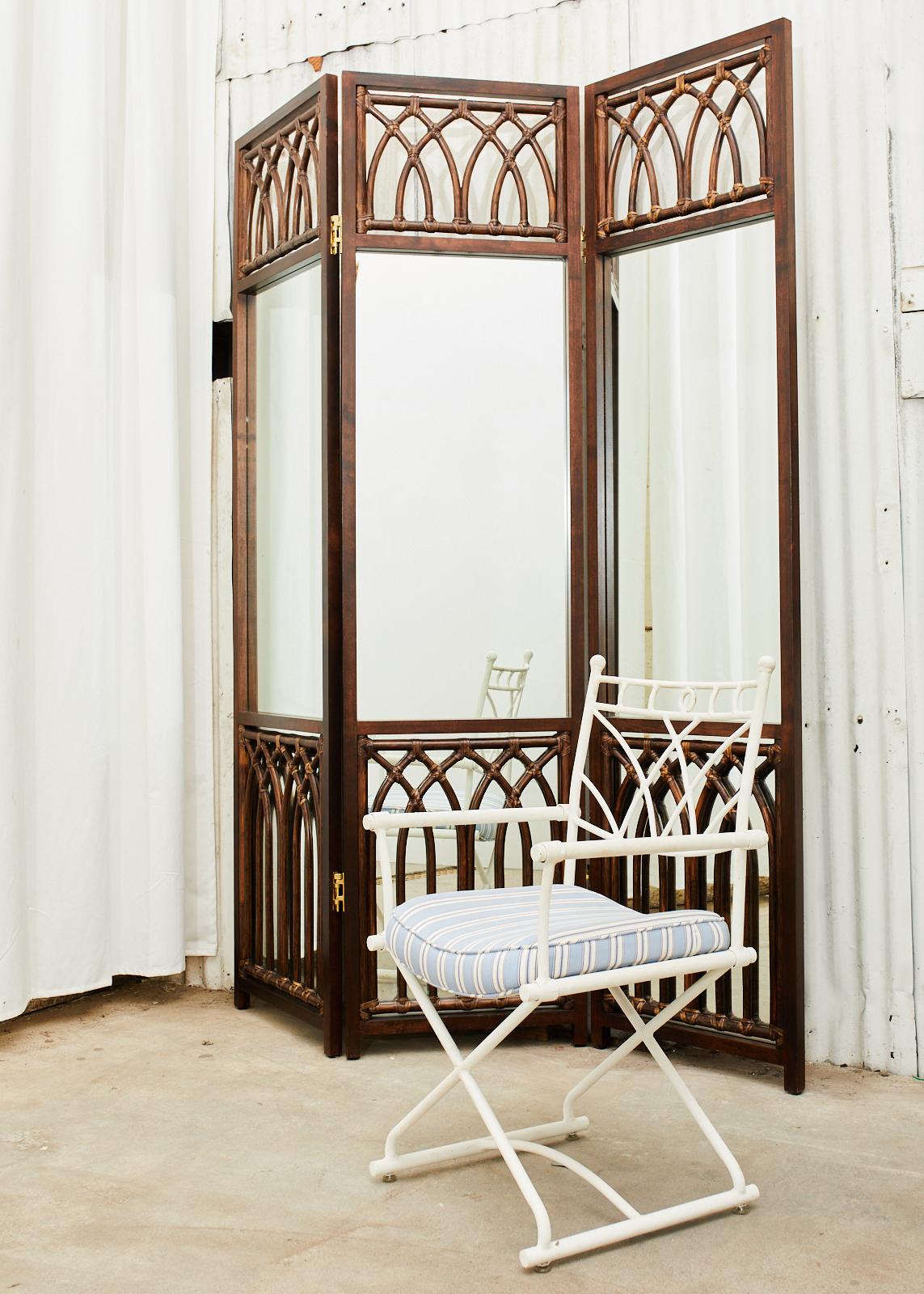 Handsome bamboo rattan folding three-panel dressing screen or room divider featuring a mirrored back. Hand-crafted by McGuire in the California organic modern style having a mahogany frame decorated with bamboo rattan poles in a gothic lancet arch