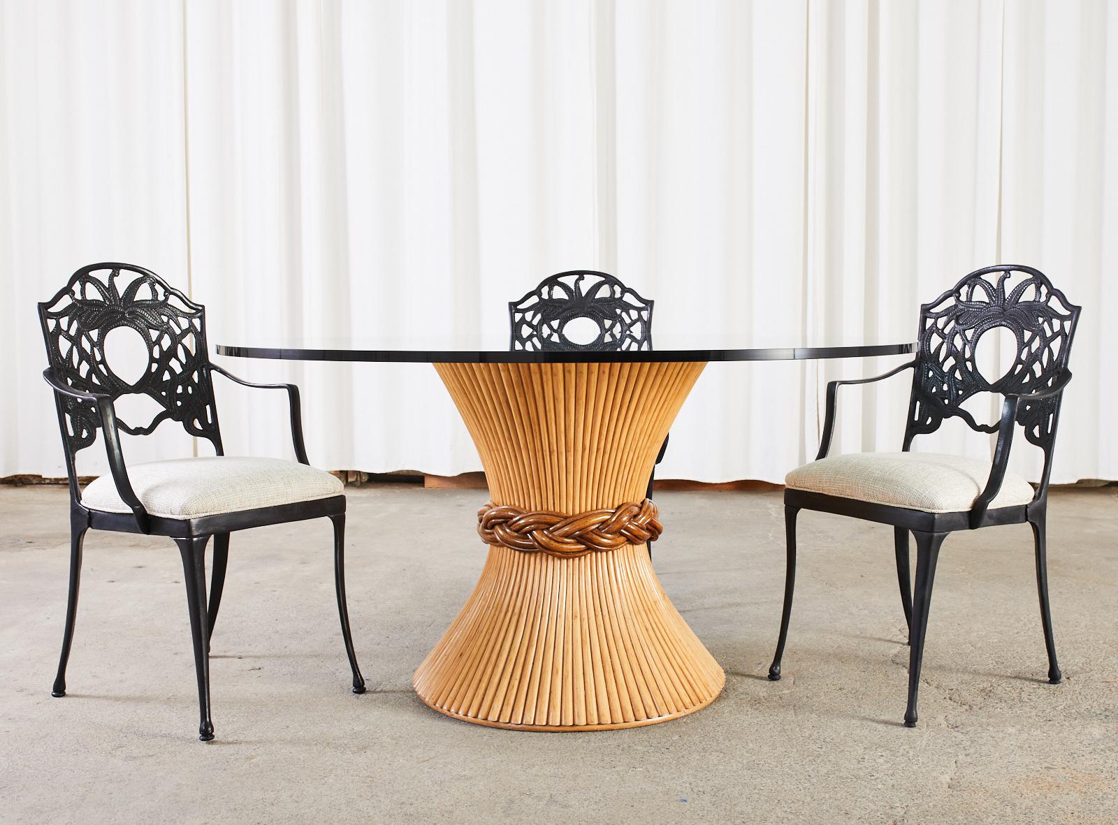 Genuine labeled McGuire rattan round glass top dining table made in the California organic modern style. The base features an hourglass form of bundled rattan with a braided waist in a rich contrasting shade. The table is topped with a genuine