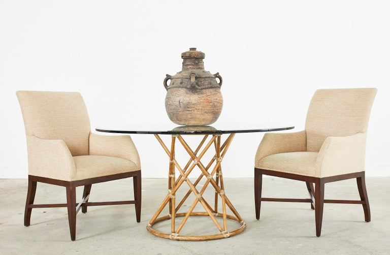 Gorgeous organic modern glass top dining table or center table made by McGuire. The table features a bamboo rattan pedestal base with a waisted hourglass form. Constructed from two rattan rings conjoined by criss-cross rattan poles lashed together