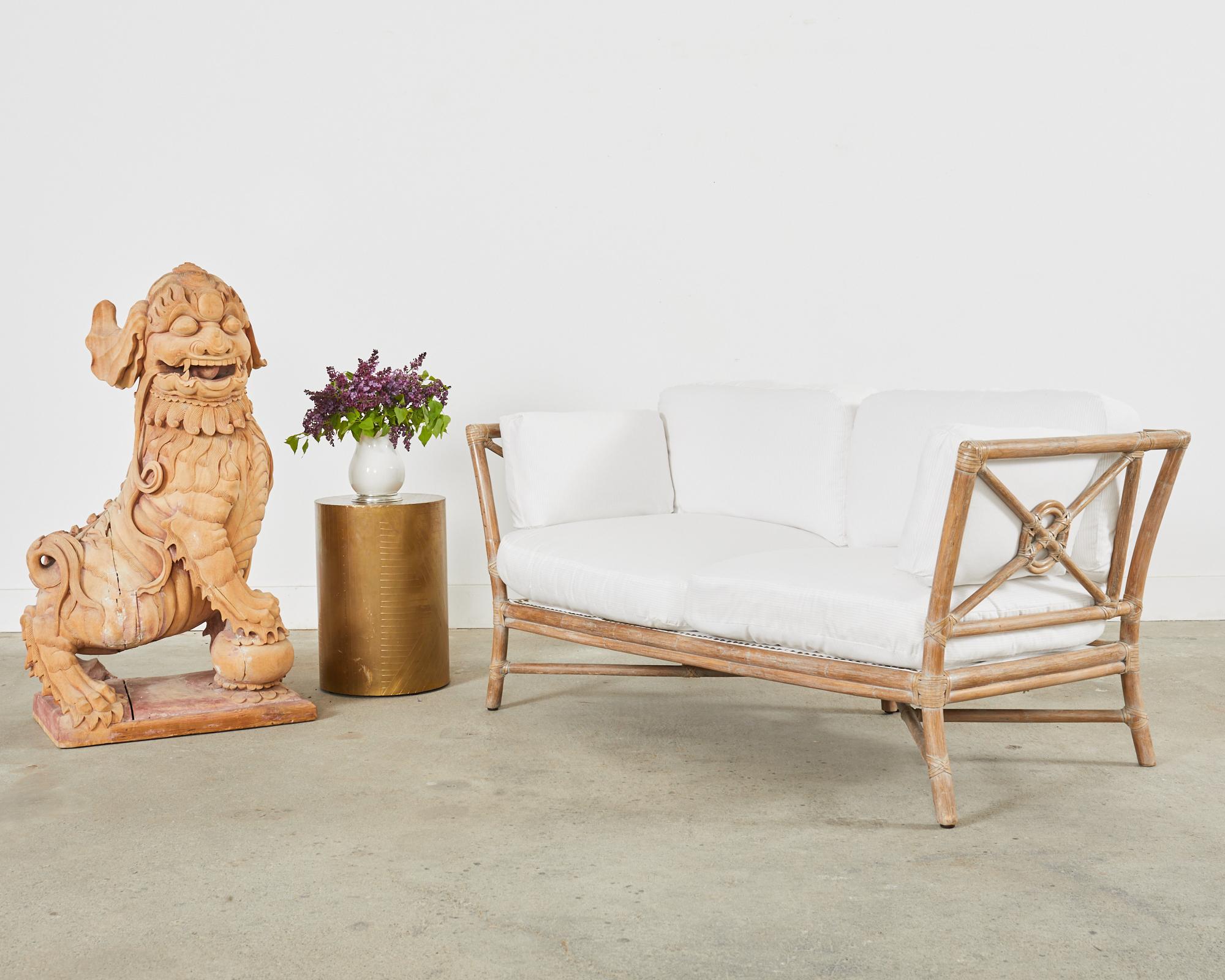 Genuine McGuire rattan sofa or settee made in the California coastal organic modern style. The settee features an iconic target motif design on the back and sides designed by Elinor McGuire. Constructed from thick rattan poles with an intentionally