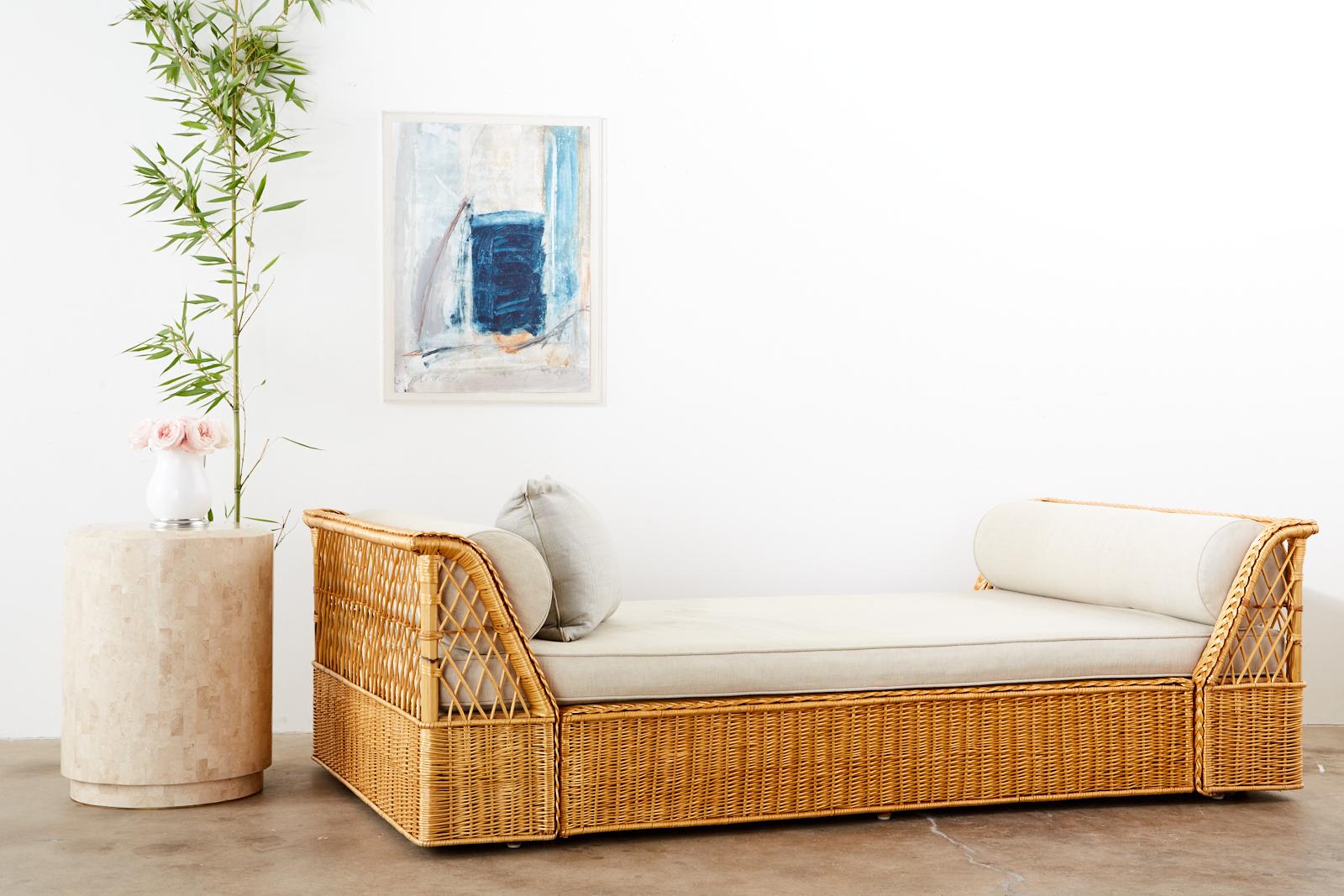 Rare, genuine McGuire rattan wicker daybed made in the California organic modern style. The bed features a rattan frame enclosed with woven wicker and an open fretwork design on each side. Topped with a fitted cushion and matching bolster pillows.