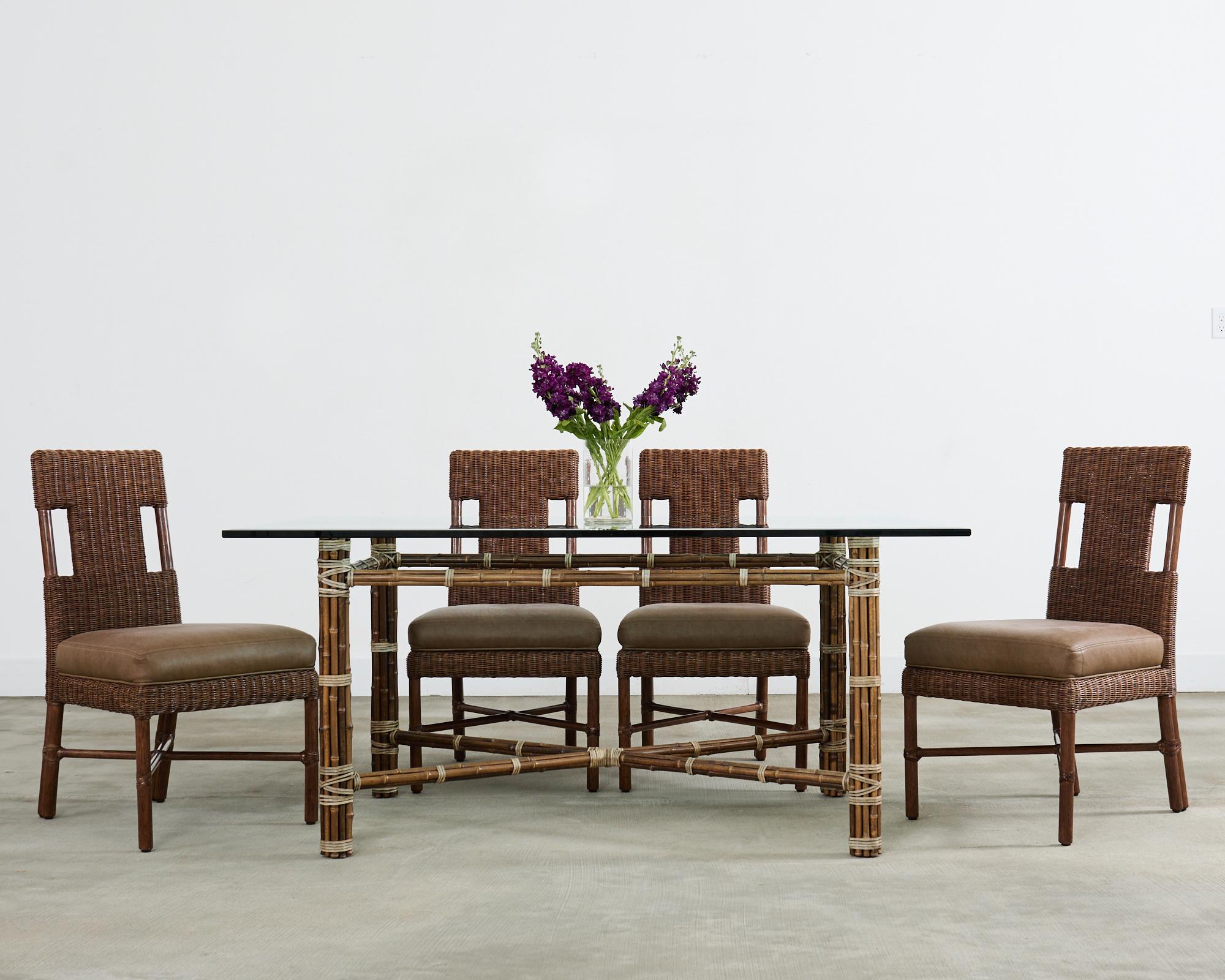 Genuine McGuire bamboo dining table made in the Califonia Coastal organic modern style. The bespoke table features a rare design seldom seen with  simple X form stretchers conjoining the legs. The table has an iron base painted golden gate orange