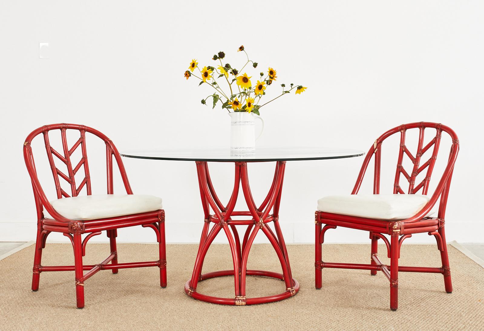Distinctive McGuire rattan pedestal dining table or center table featuring a whimsical red lacquered finish. The table is crafted from rattan poles in a basket design having an hourglass or waisted form. Excellent joinery and craftsmanship with an