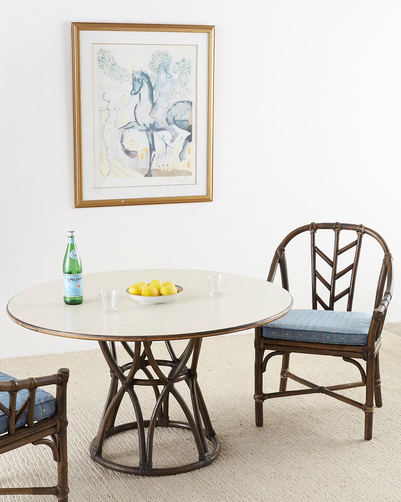 Stylish organic modern round game table or dining table made by McGuire. Features a bamboo rattan basket base with an hourglass form reinforced with leather rawhide laces. The round top has a formica style material with a bamboo edge. Made in the