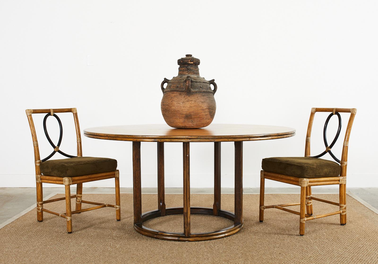 Grand McGuire ist ein moderner, runder Esstisch aus Eichenholz mit einer Oberfläche aus geriffeltem Rattan. Der große Tisch hat einen Sockel aus Eichenholz, der aus zwei Eichenholzkreisen besteht, die durch fünf Eichenholzbeine miteinander verbunden