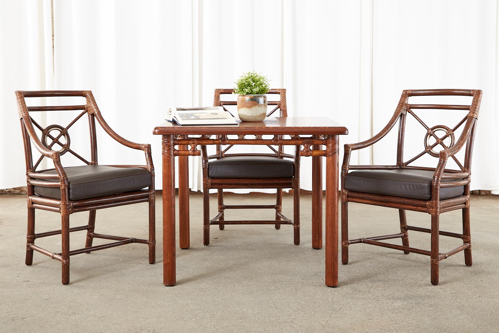 Intimate square dining table or games table made by McGuire in the California organic modern style. Crafted from oak with a thick square top featuring a rattan open fretwork style apron. The rattan is reinforced with McGuire signature leather