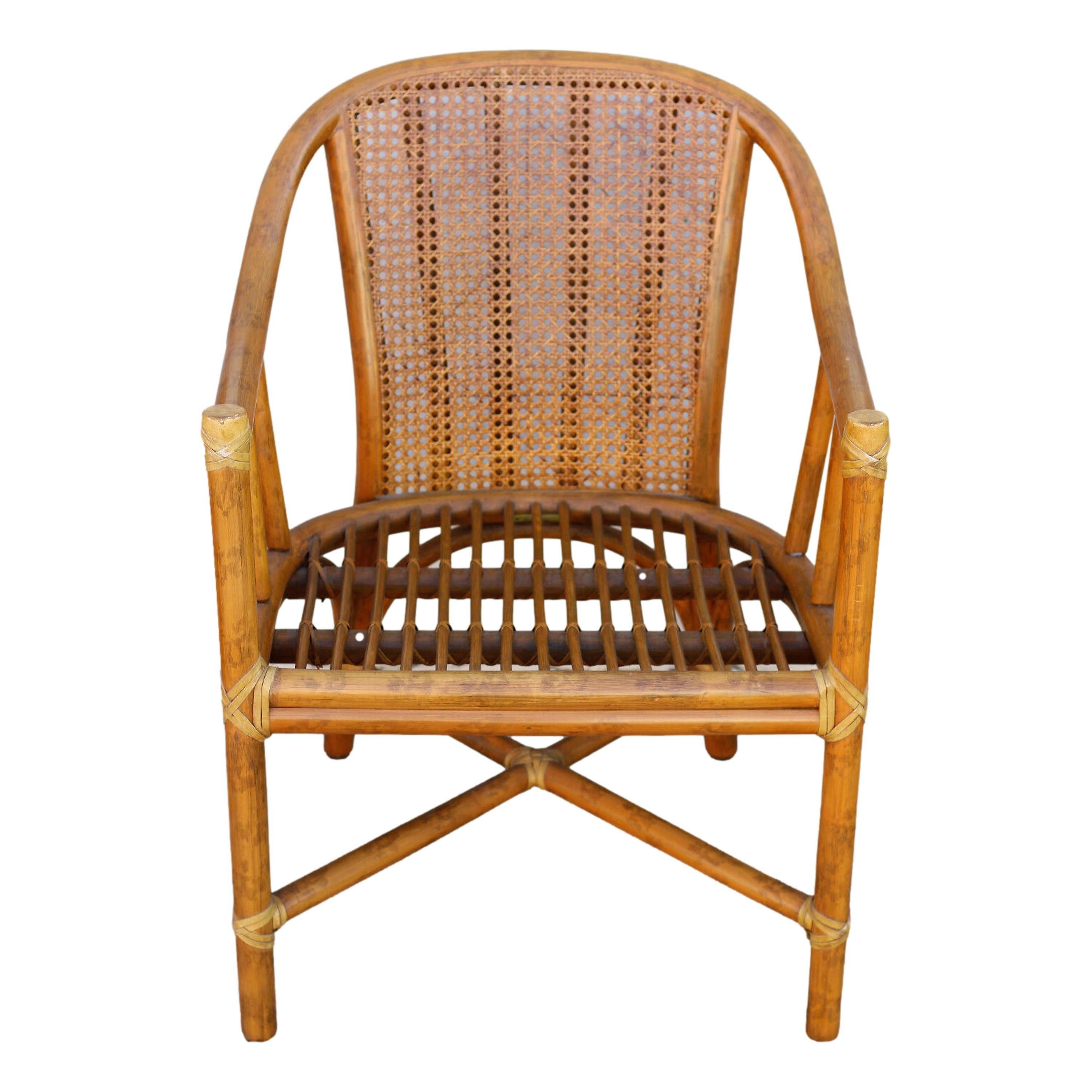 Casual luxury from McGuire San Francisco. This vintage organic modern set of four armchairs features a cane seat back and graceful frames constructed from bent rattan with curved arms and seat. Vintage seat cushions rest on a stick deck, and legs