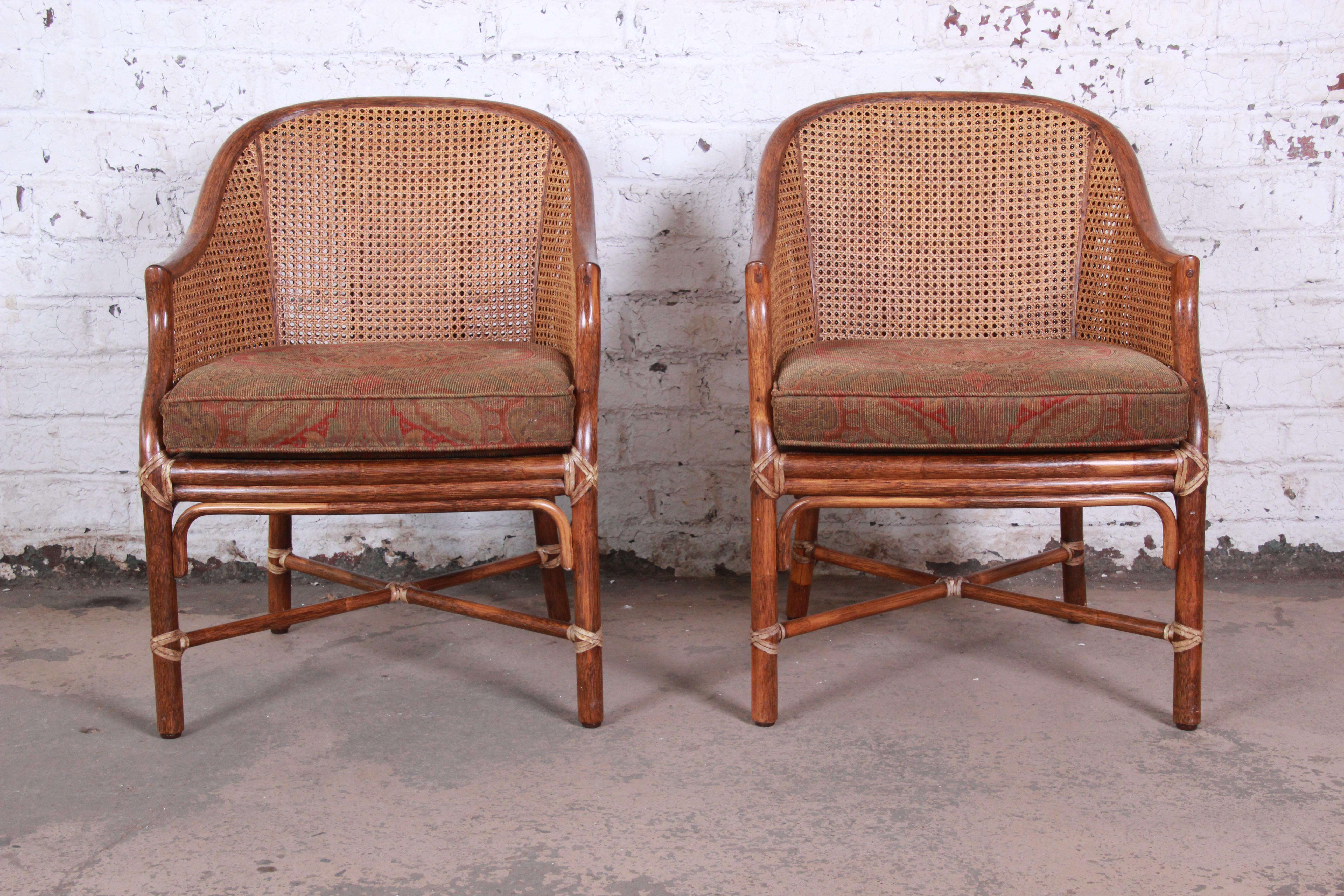 An exceptional pair of rattan and cane club chairs by McGuire of San Francisco. The chairs feature stout, expertly constructed rattan and hardwood frames with X-base stretchers and a cane back. Each chair retains the original label. The chairs are