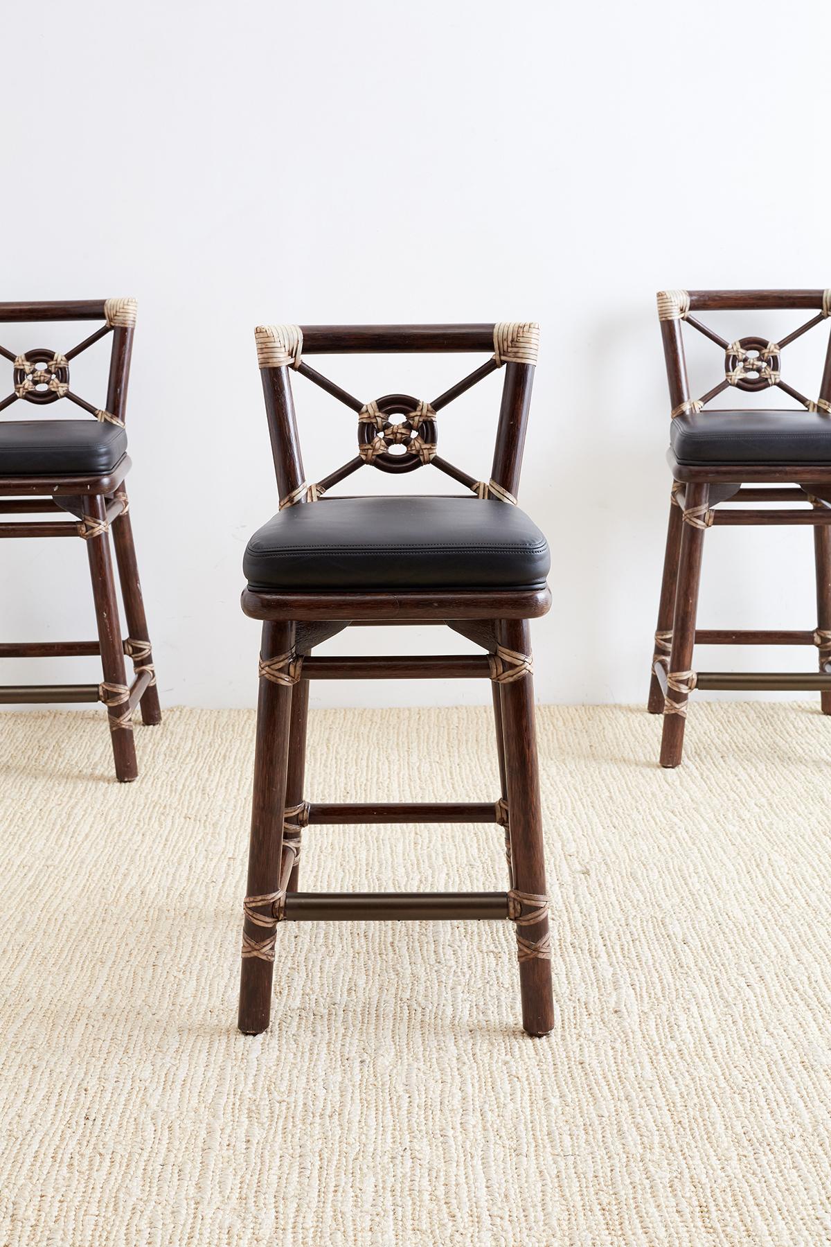 Handsome McGuire counter height barstools featuring a handcrafted, thick rattan frame with a deep espresso finish. Decorated with a target design back splat and reinforced with a contrasting leather rawhide in a light cream color. Heavy and solid
