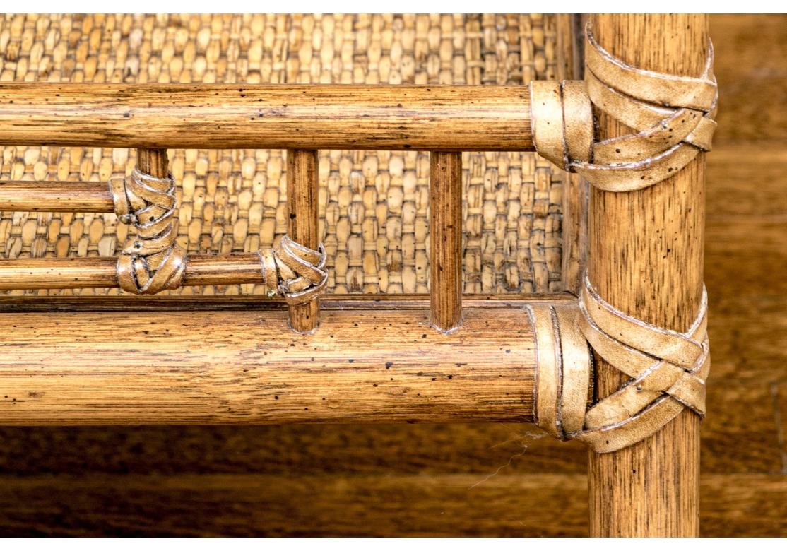 Exceptional McGuire occasional table with a circular glass top over a decorative woven center with banded rings around the perimeter. Raised over four gently curved Leather bound rattan legs wrapped around the corners of a gallery with an open lower