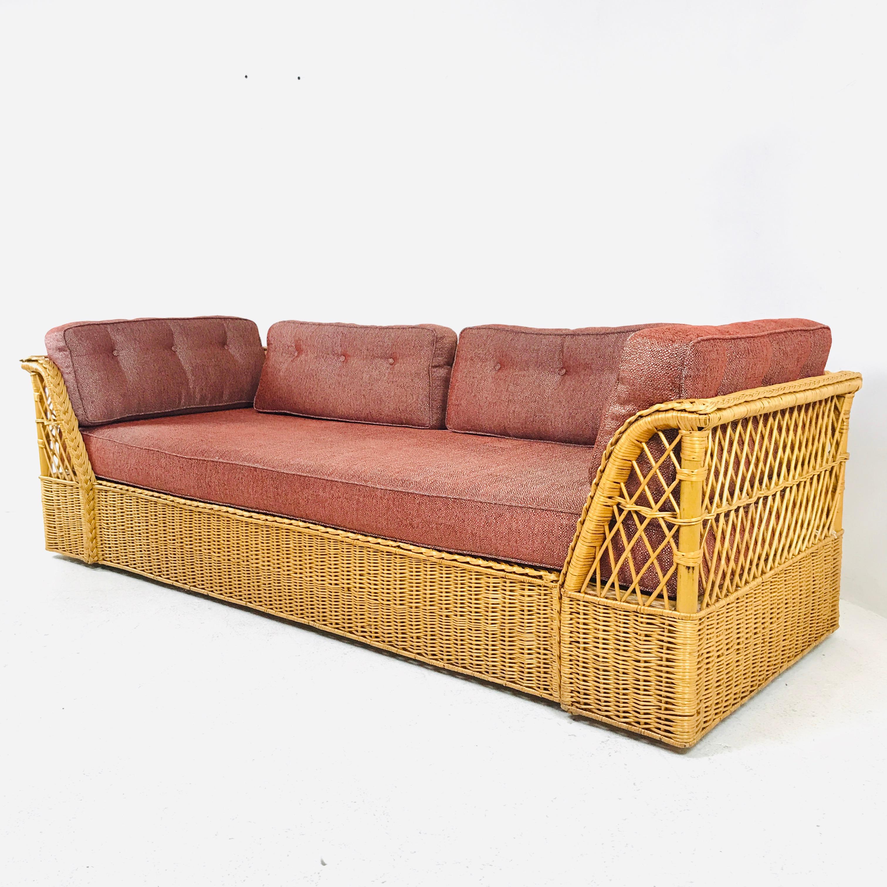 Gorgeous rattan wicker sofa made by McGuire. Features a rattan and wood frame covered with woven wicker. The bottoms have a tight weave pattern while the tops of the side and back have an open fretwork geometric design. The arms have a decorative