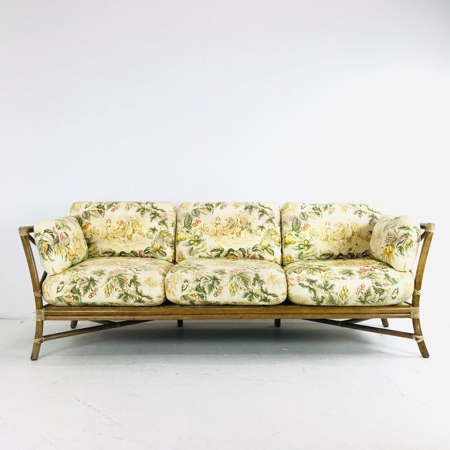 Iconic 3 seat rattan sofa by McGuire. Solid construction, rawhide corner wraps, bullseye back, great quality and form, circa mid-late 20th century.