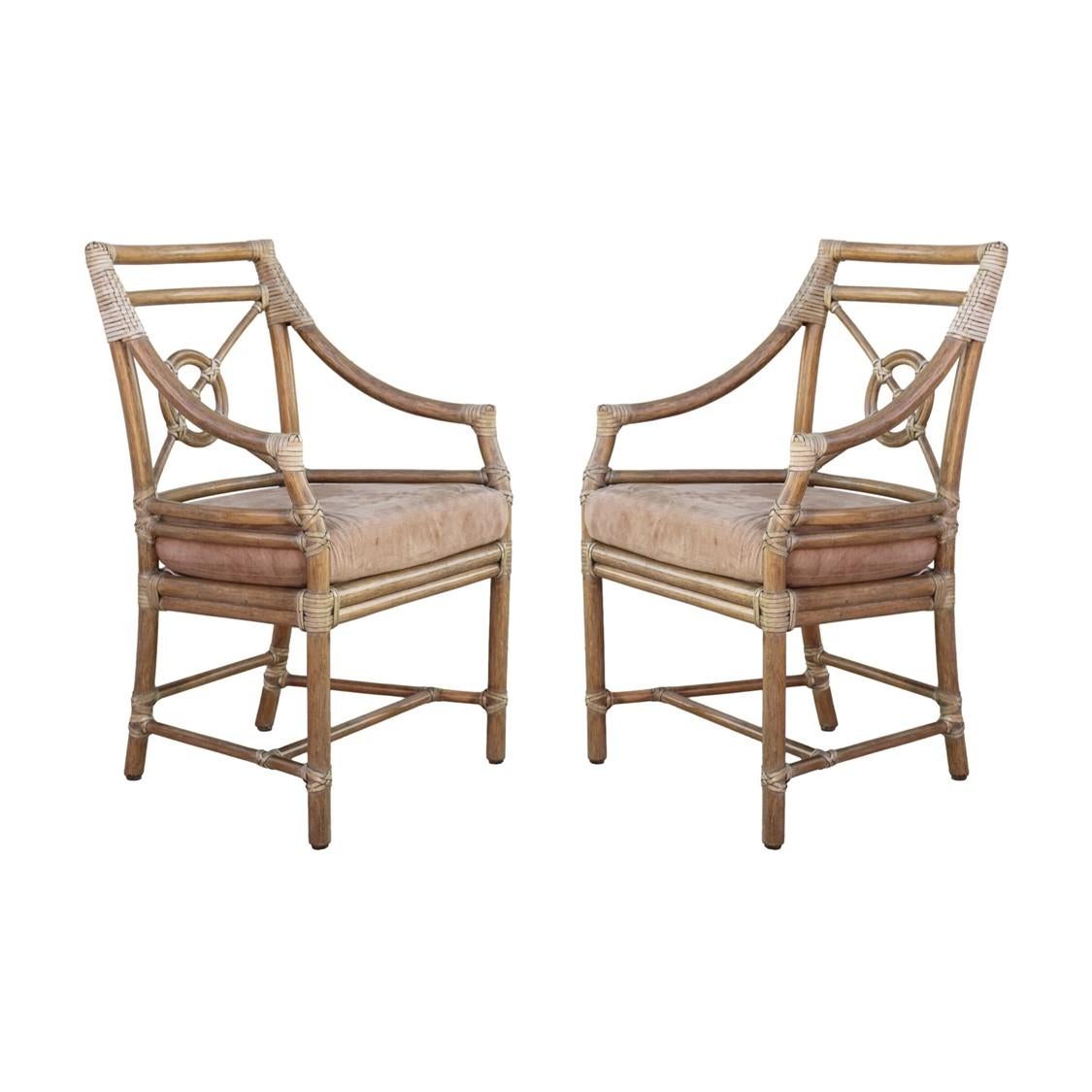 A pair of rattan arm chairs or dining chairs designed by breakthrough innovator Elinor McGuire in the California organic modern style. These impeccably crafted chairs display an open rattan back, which frames McGuire's iconic Rattan Target design.