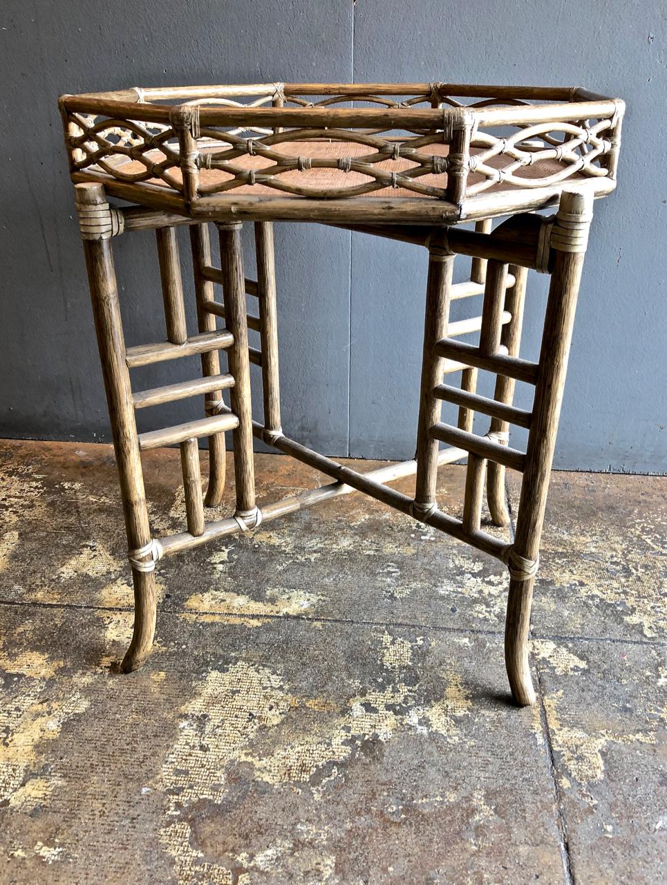 This is a very chic McGuire bamboo and cane tray detailed with fretwork that sits on a folding bamboo stand. This little table would integrate into many design scenarios from traditional to cottage to midcentury. The table most probably dates to the