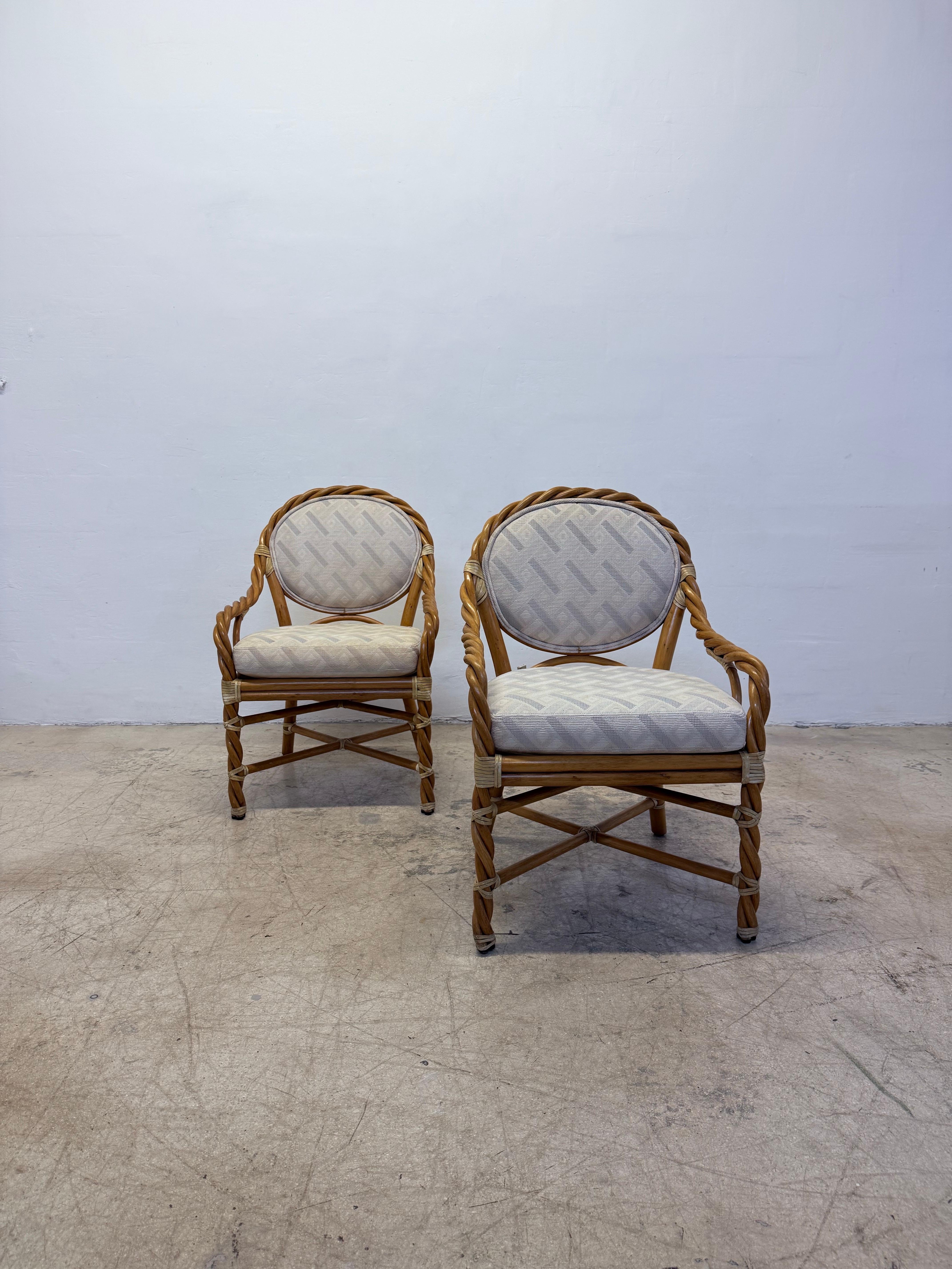 Pair of circa 1980s McGuire twisted rattan chairs with leather binding and seat and back cushions. Fabric on seat and back show some wear and new upholstery is recommended.
