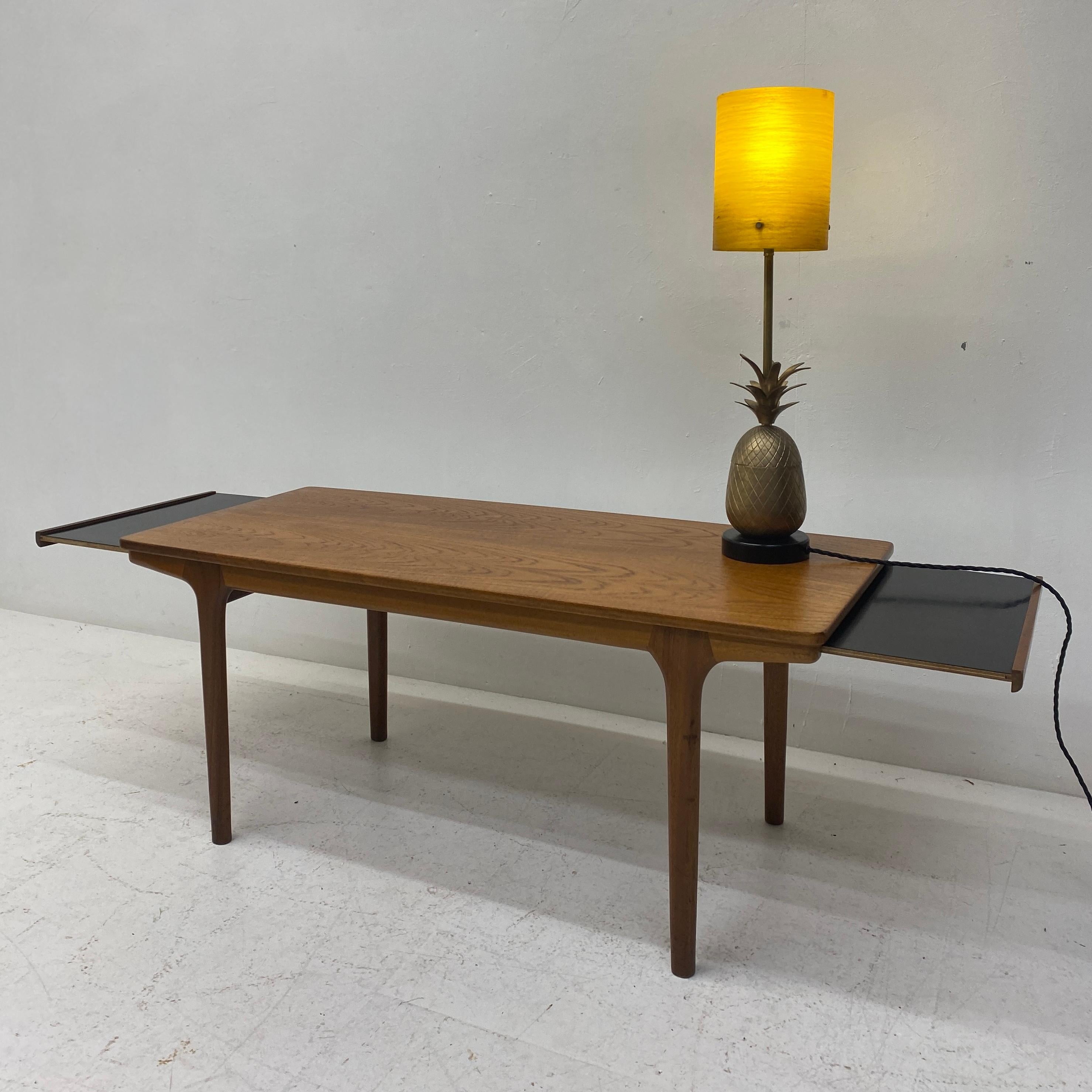 A very attractive midcentury coffee table by Scottish McIntosh & Co Ltd. Teak top, frame & legs & pullout extensions at either side in black melamine. Great leg detail. The coffee table is a very elegant rectangular shape & nice for a smaller