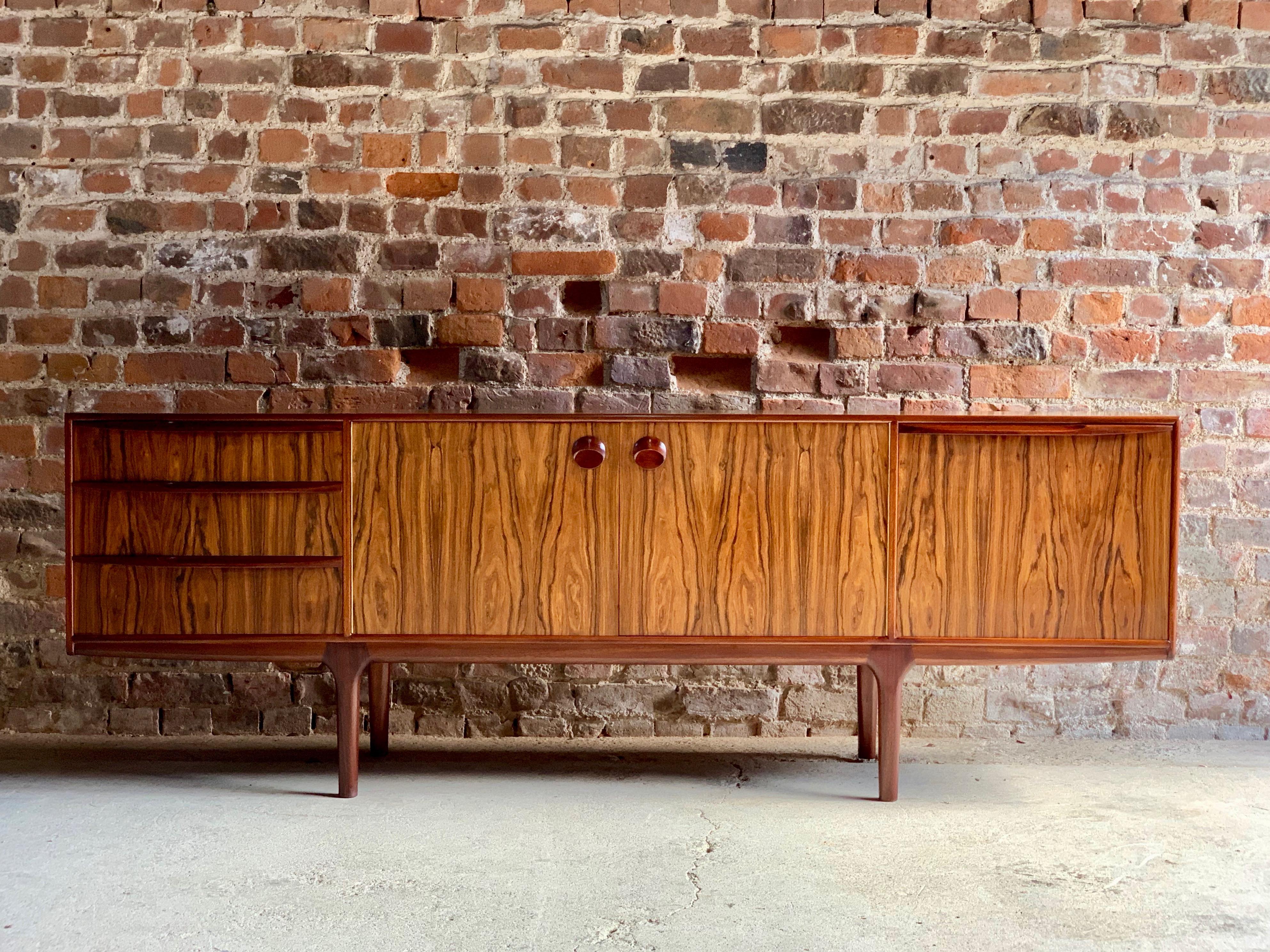 A stunning midcentury design rosewood sideboard credenza designed by Tom Robertson for AH McIntosh of Kirkcaldy, Scotland, circa 1960s, the beautiful rectangular top with stunning rosewood grain over centre section double doors with circular door