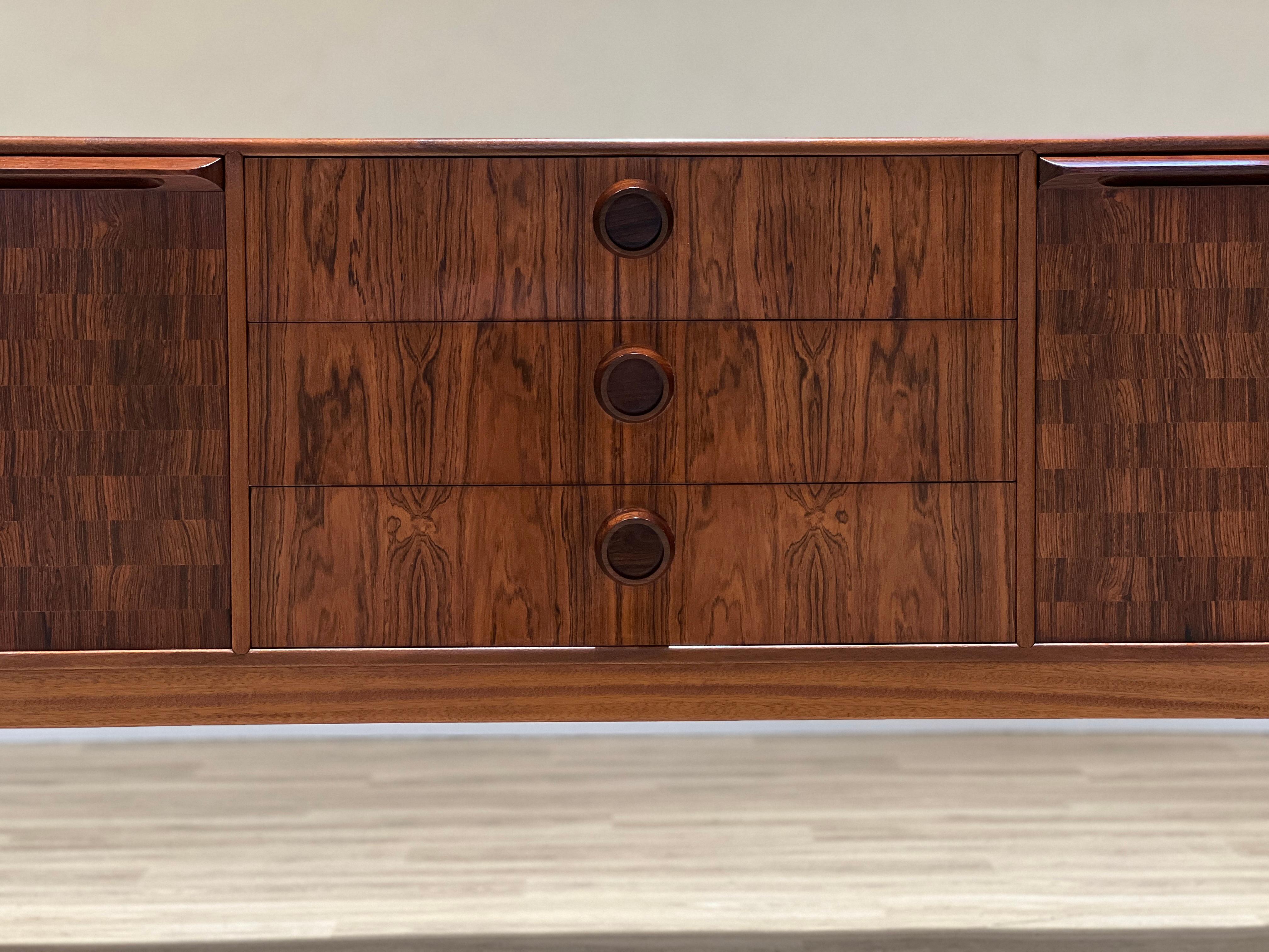 Stunning and unusual mid-century sideboard designed by Tom Robertson for cabinetmaker A.H. McIntosh in Scotland for the well-known Dunoon collection in rosewood.

This piece is characterised by the artisan work and the beauty of its organic round