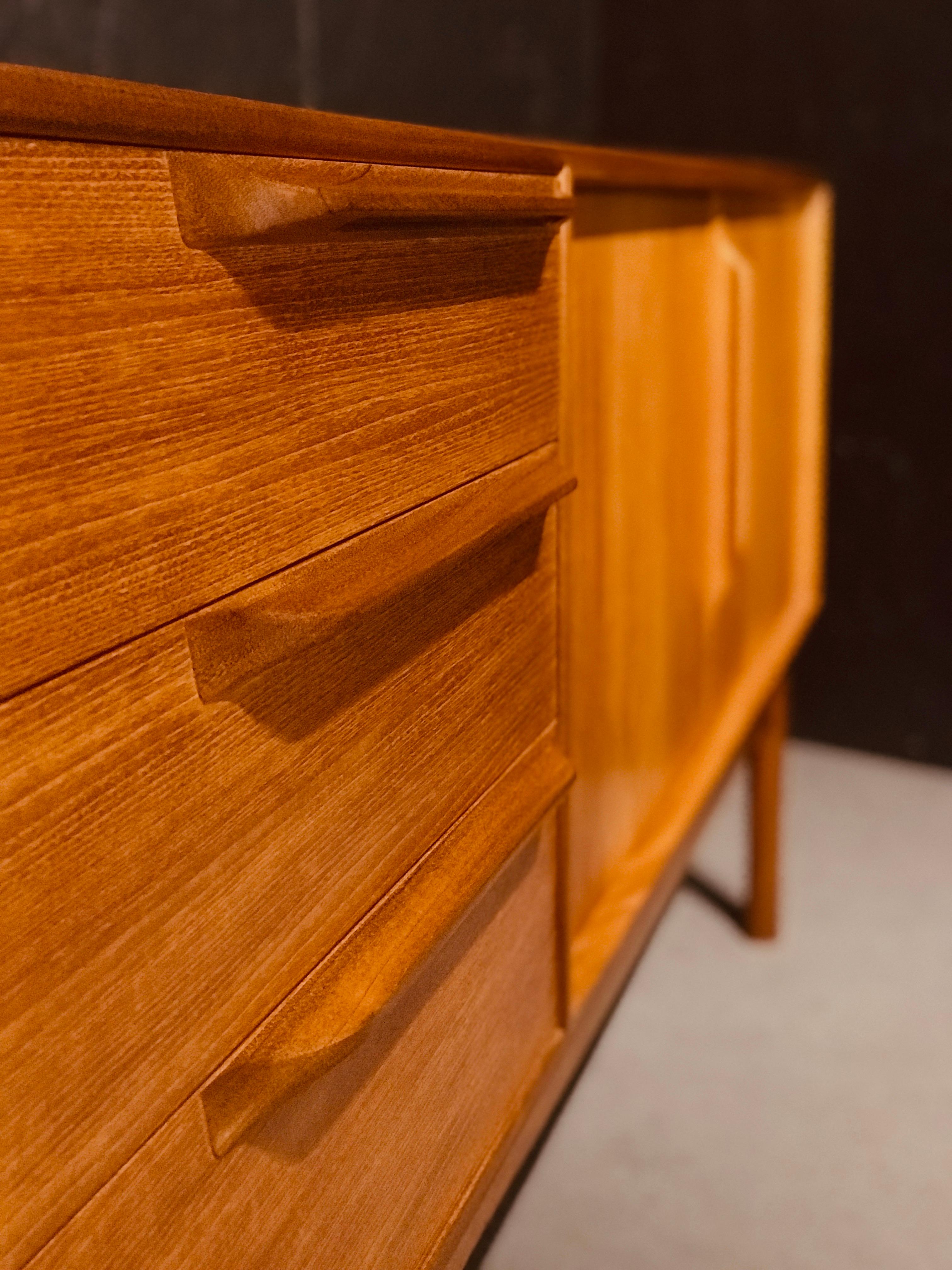 Tom robertson designed this beautiful sideboard in scotland in the early ‘70s for the well-known cabinet maker a.h. Mcintosh. The sideboard has two sections, one bank of three drawers, the top one lined up for the cutlery, and an, on its right, a