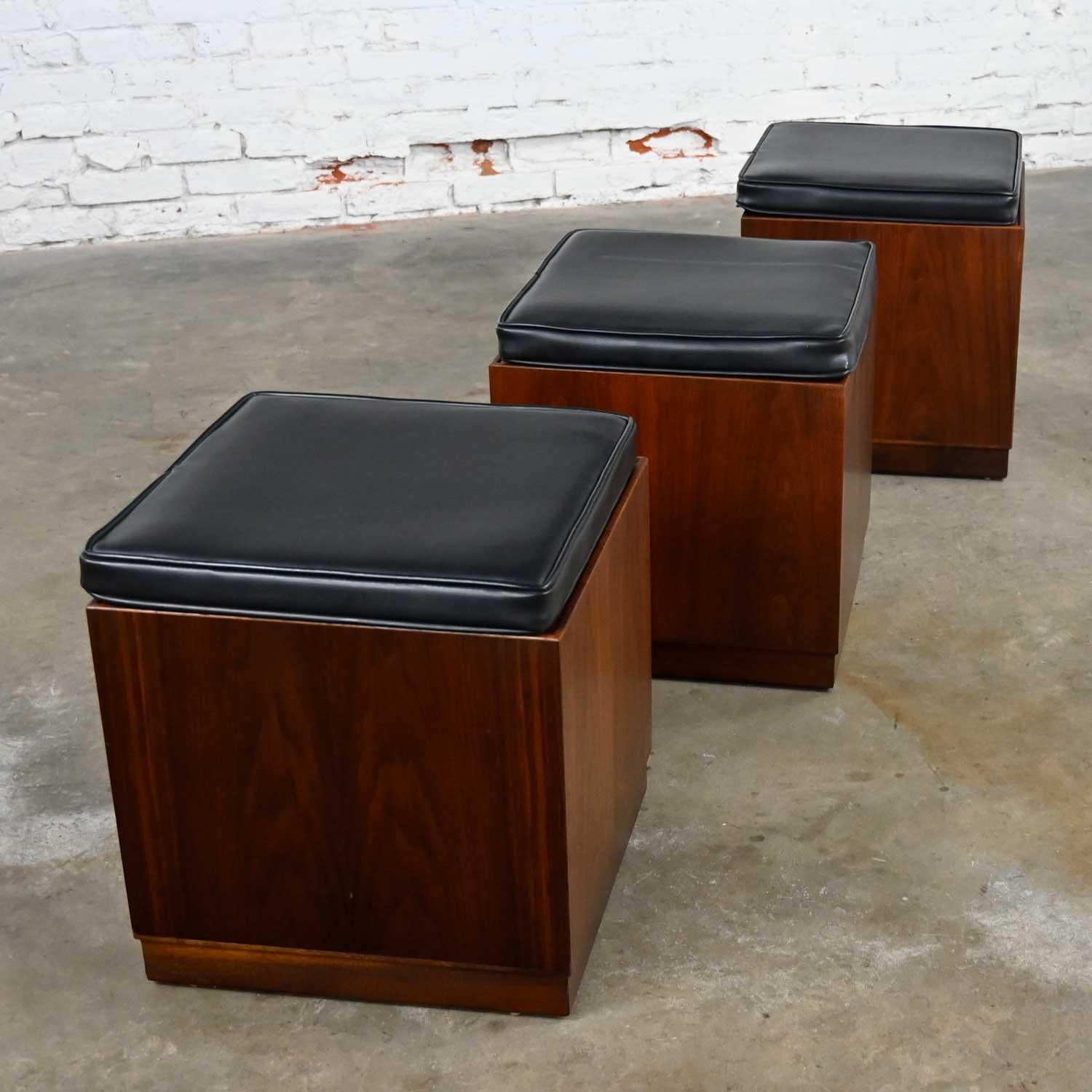 Amazing Mid-Century Modern trio of square walnut cube stools number 42102-01 with black faux leather upholstered tops by Jack Cartwright for Founders Furniture’s Patterns 7 line. Beautiful condition, keeping in mind that these are vintage and not