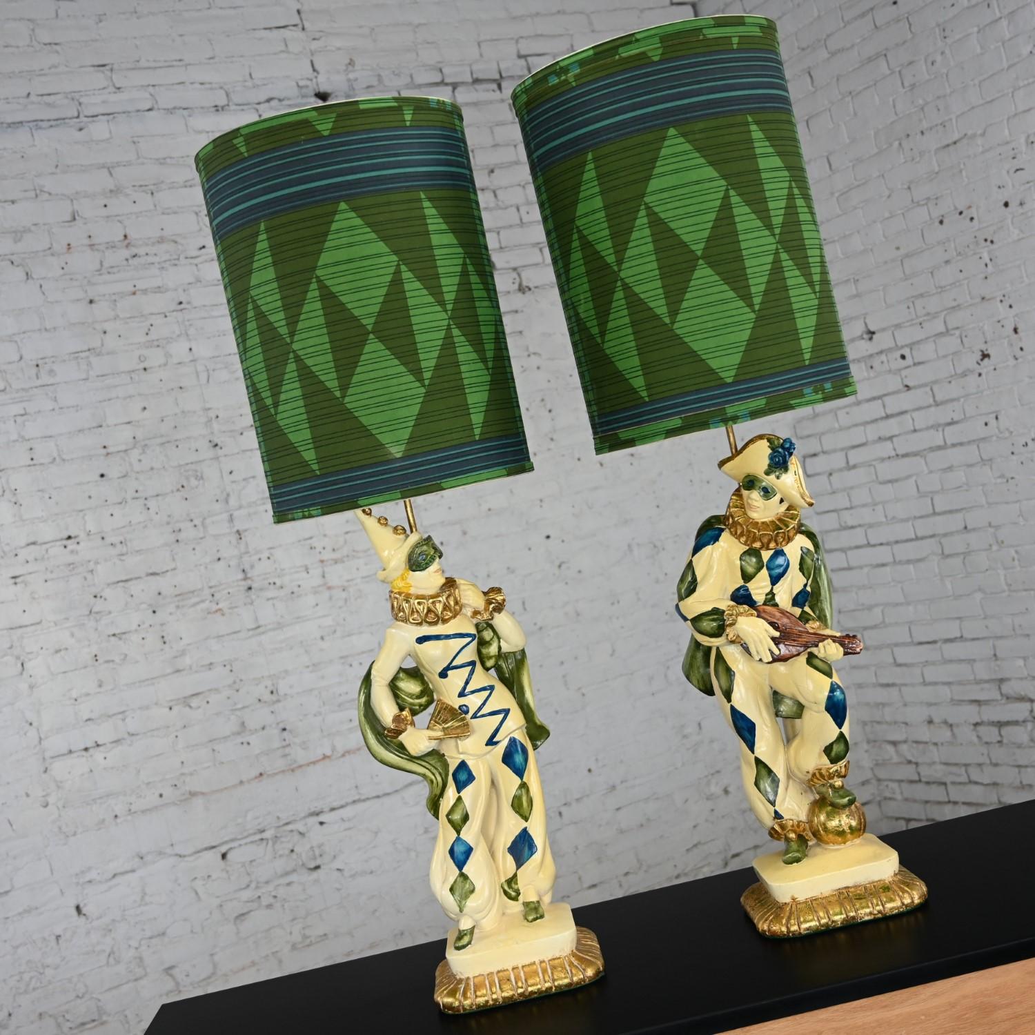 Joyful vintage MCM (Mid-Century Modern) Art Deco figural jester or harlequin table lamps in the style of Marbro, a pair. Comprised of molded plaster, blue, green, and gold hand painted details, antiqued gold painted stems, brass plated steel