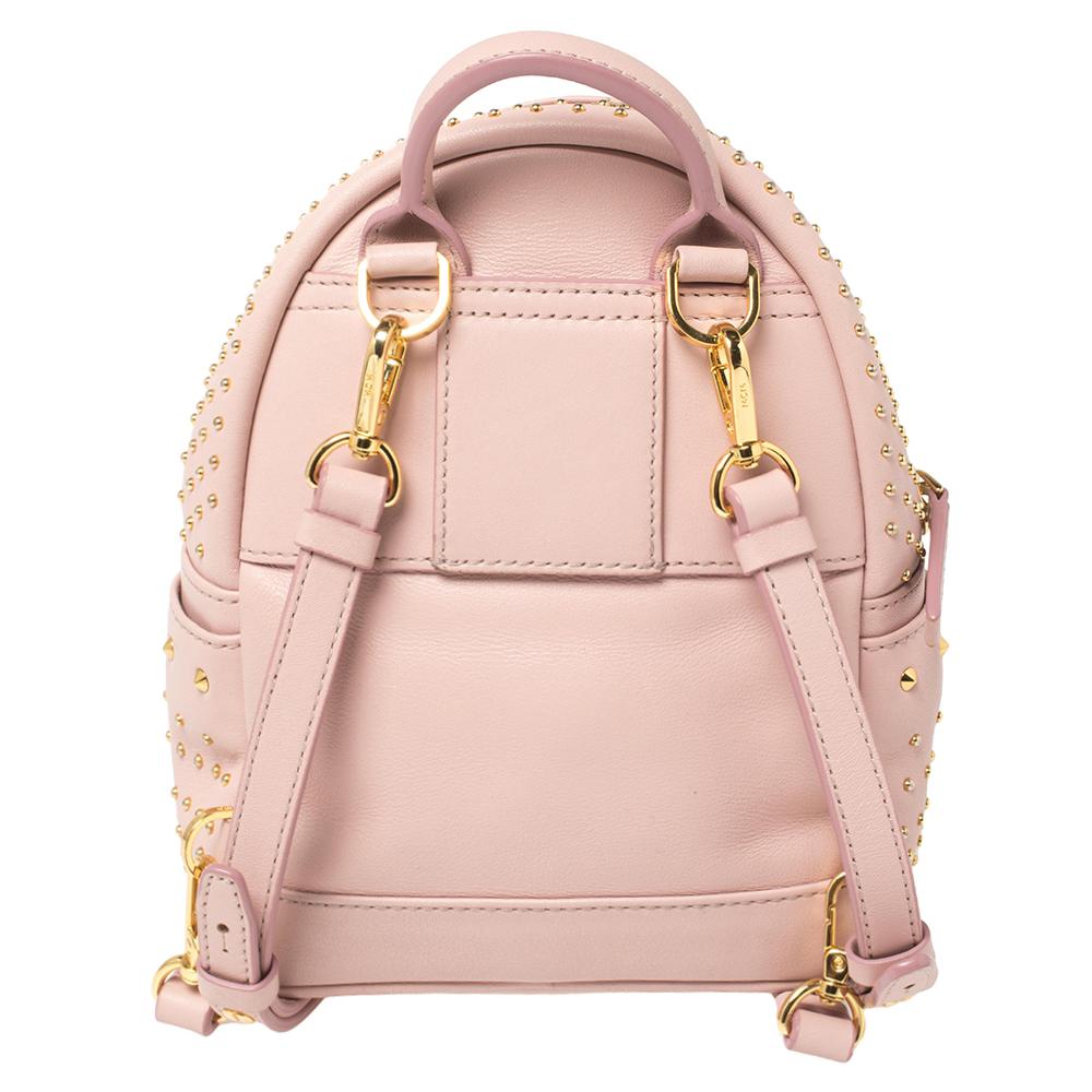This MCM Stark-Bebe Boo backpack will come in handy for daily use or as a style statement. It is crafted from pink leather and designed with gold-tone studs all over in varied sizes. It features a front zip pocket and two slip pockets on the sides.