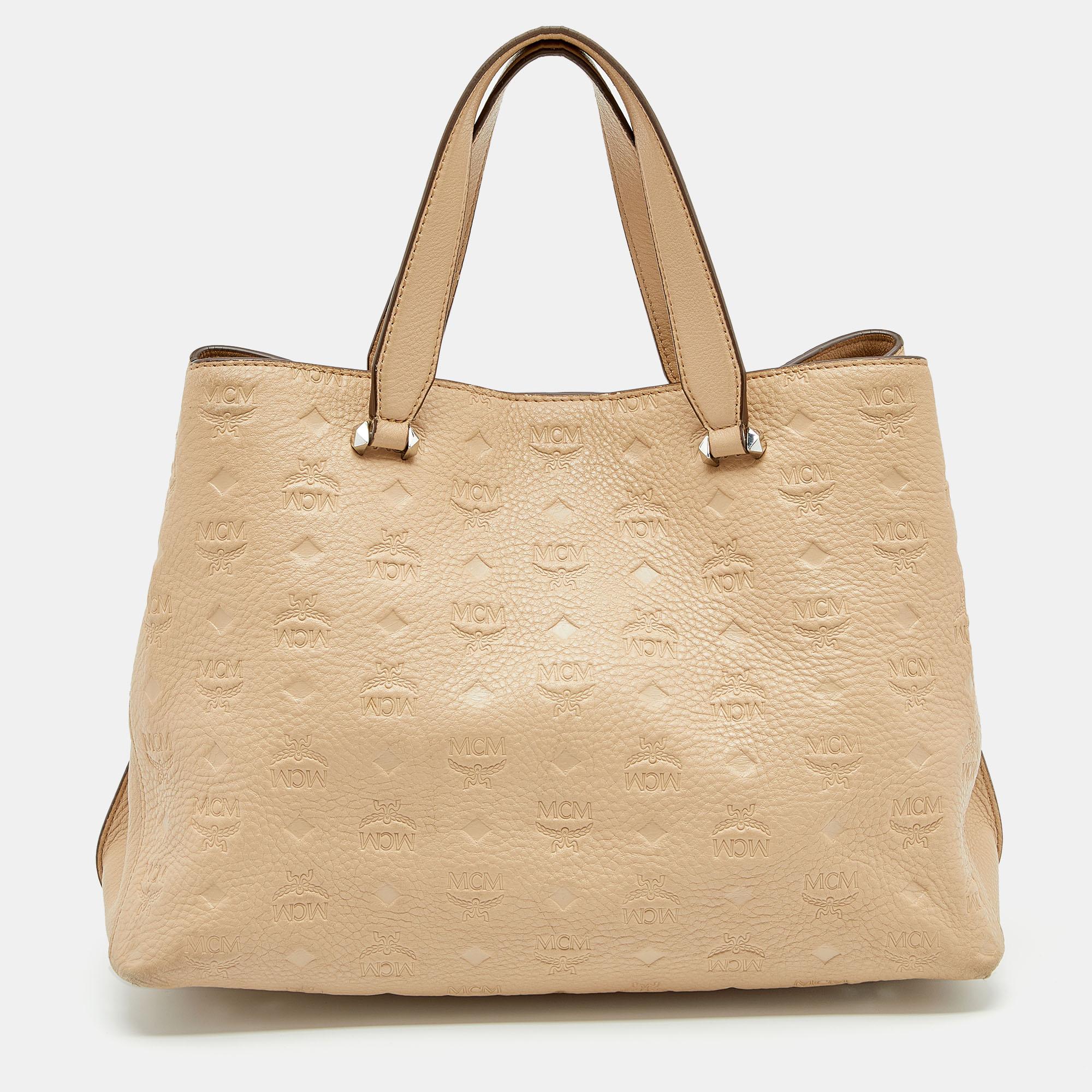 Coming from MCM is this beige tote that is the perfect day bag. It is crafted from leather into a structured shape and flaunts silver-tone details, dual handles, and a turn-lock closure that reveals a capacious interior for your belongings. The tote