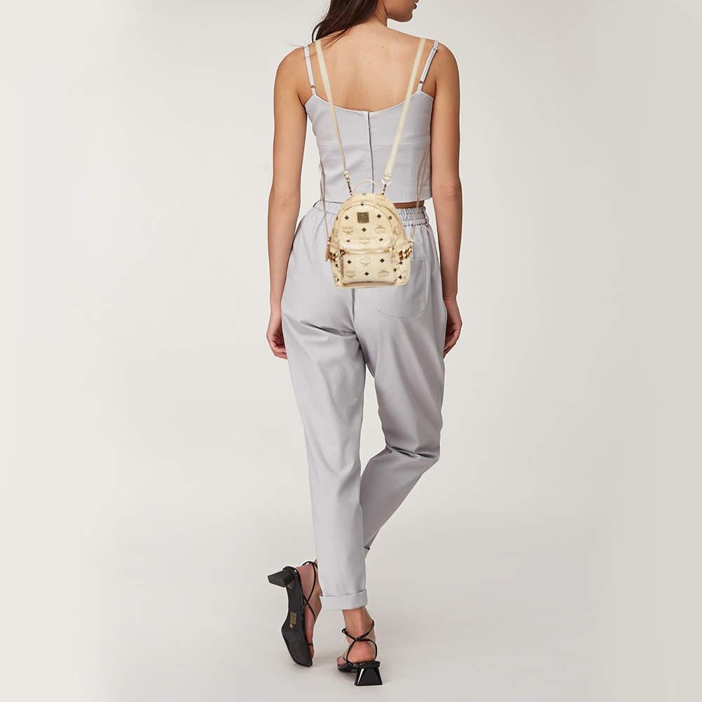 Ce sac à dos MCM Stark Bebe Boo sera très pratique pour un usage quotidien ou pour affirmer son style. Il est réalisé en toile enduite Visetos beige et en cuir et est orné de clous dorés sur les côtés. Il est doté d'une poche frontale zippée et de