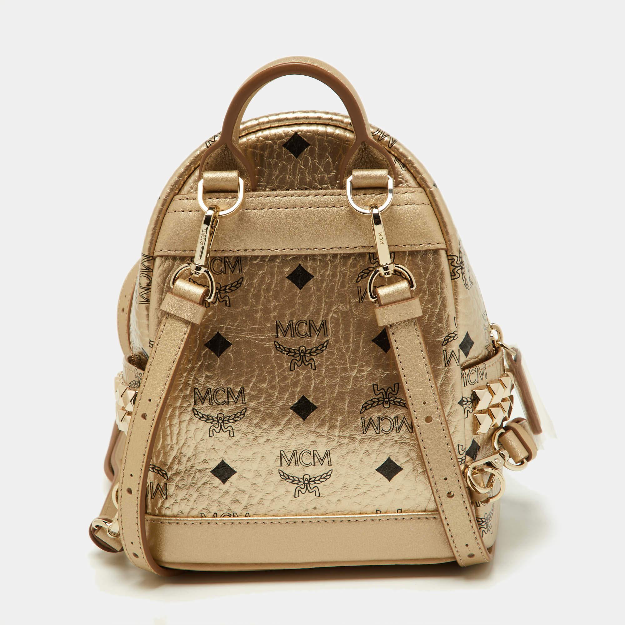 This MCM Stark-Bebe Boo backpack will come in handy for daily use or as a style statement. It is crafted from Visetos-coated canvas and leather and designed with gold-tone metal. It features a front zip pocket and two slip pockets on the