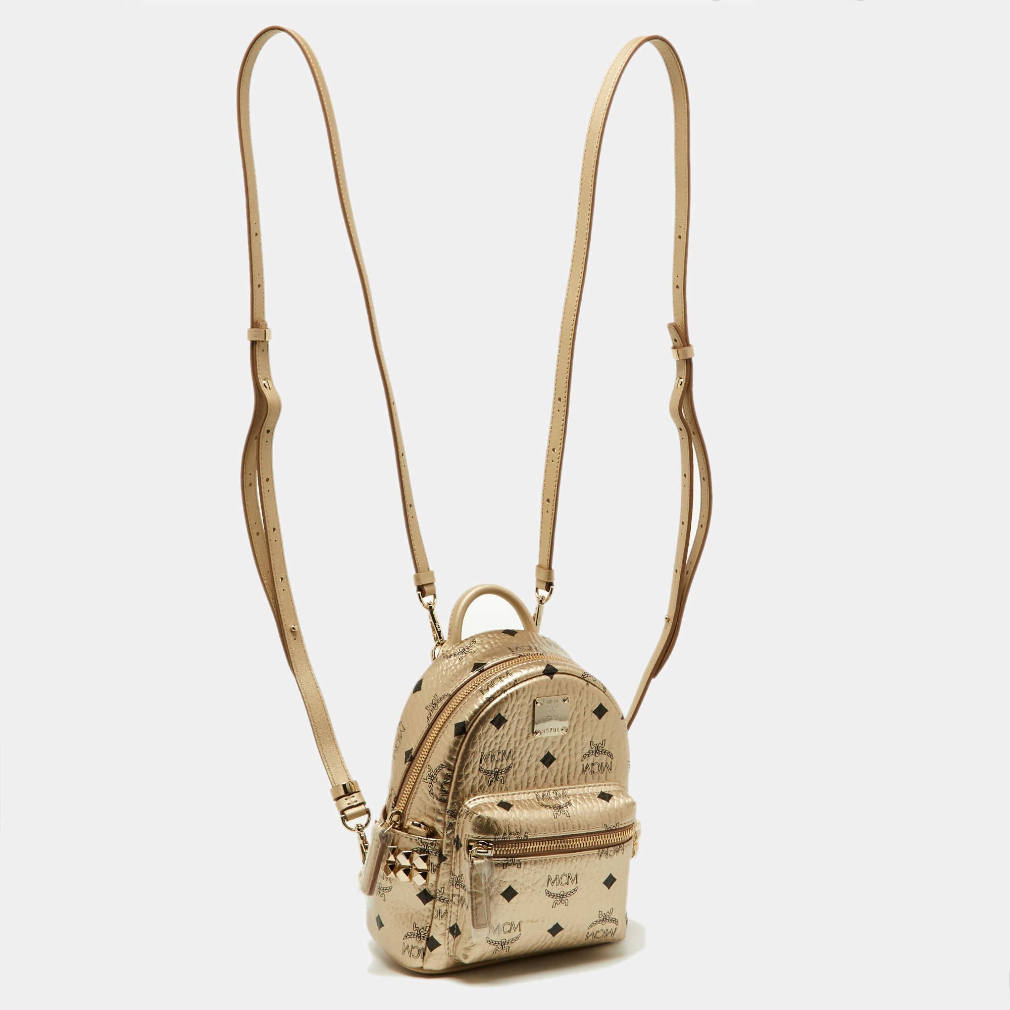 This MCM Stark-Bebe Boo backpack will come in handy for daily use or as a style statement. It is crafted from Visetos-coated canvas and leather and designed with gold-tone metal. It features a front zip pocket and two slip pockets on the sides.

