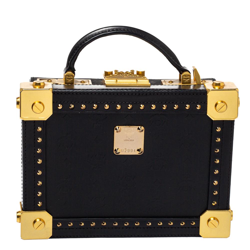 Adorned with decorative gold-tone accents on the exterior, this bag from MCM has a structured shape and a refined style. The bag comes crafted from black leather and flaunts a top handle and a shoulder strap. The trunk-style bag opens to a