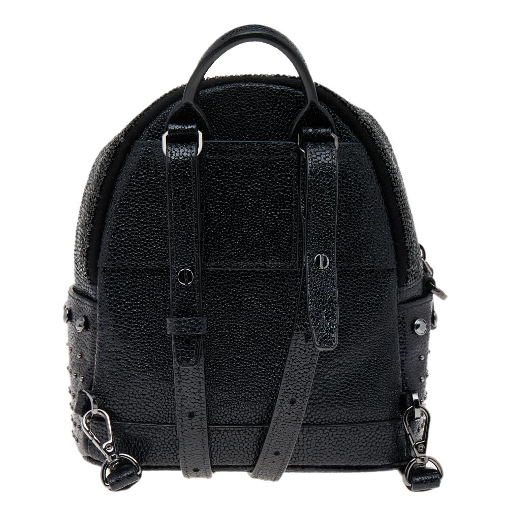 This stunning MCM backpack will come in handy for daily use or as a style statement. It is crafted from leather and suede and designed with crystals, a front pocket, and a spacious interior secured by a zipper. Two shoulder straps, silver-tone