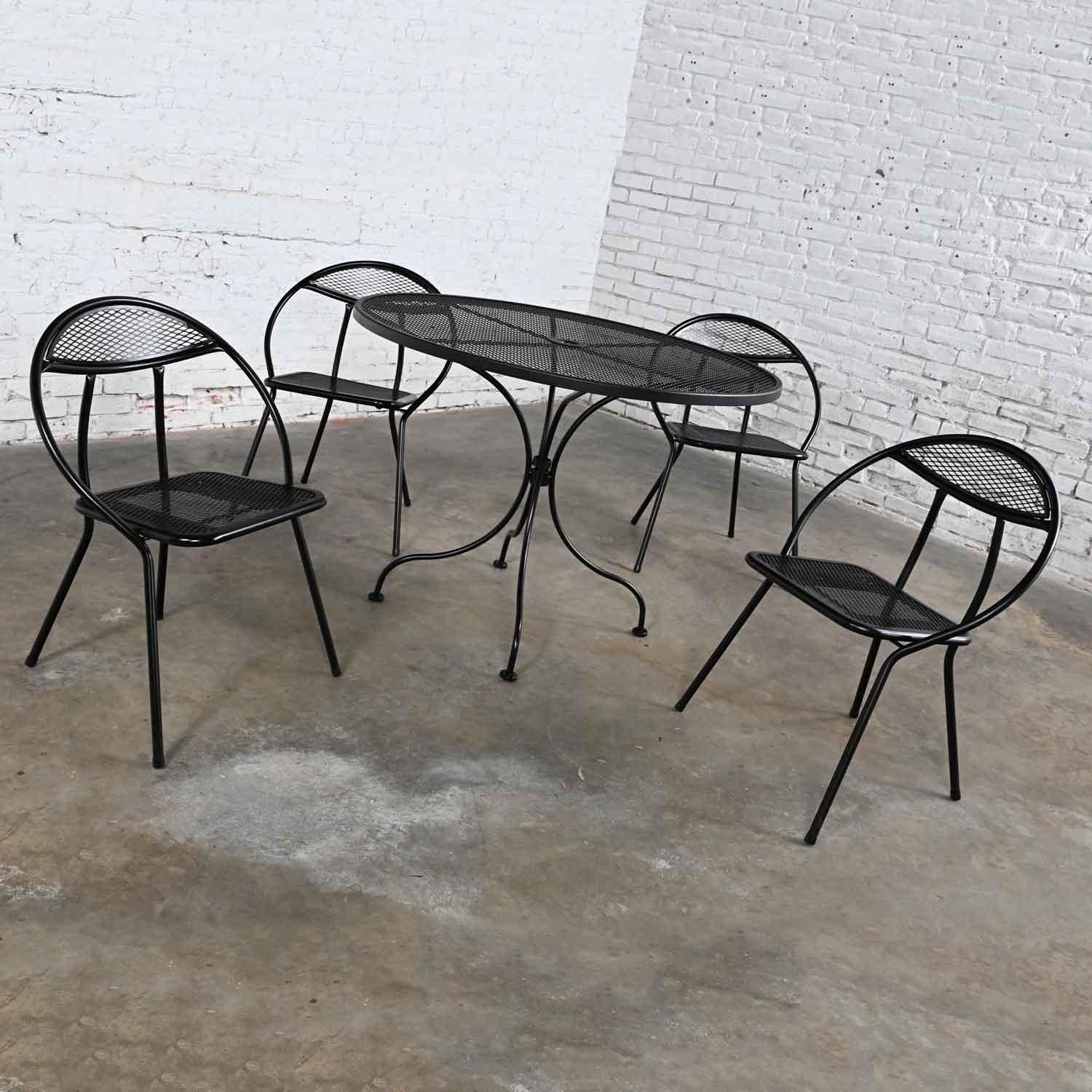 Awesome vintage MCM (mid-century modern) black painted outdoor dining set of 4 Rid-Jid Hoop chairs comprised of tubular steel folding chairs paired with a newer wrought iron round dining table with expanded metal top, umbrella hole, and solid rod