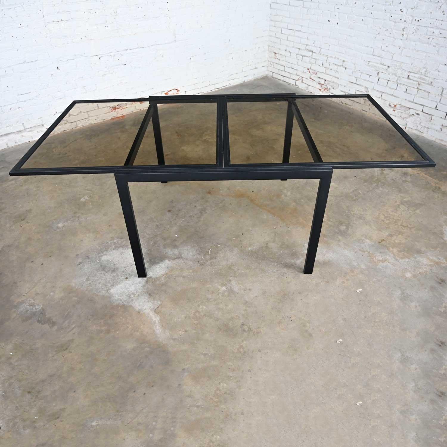 Fabulous MCM (a.k.a. Mid-Century Modern) to Modern black powder coated metal smoked glass square expanding table attributed to DIA (a.k.a. Design Institute of America.) Beautiful condition, keeping in mind that this is vintage and not new so will