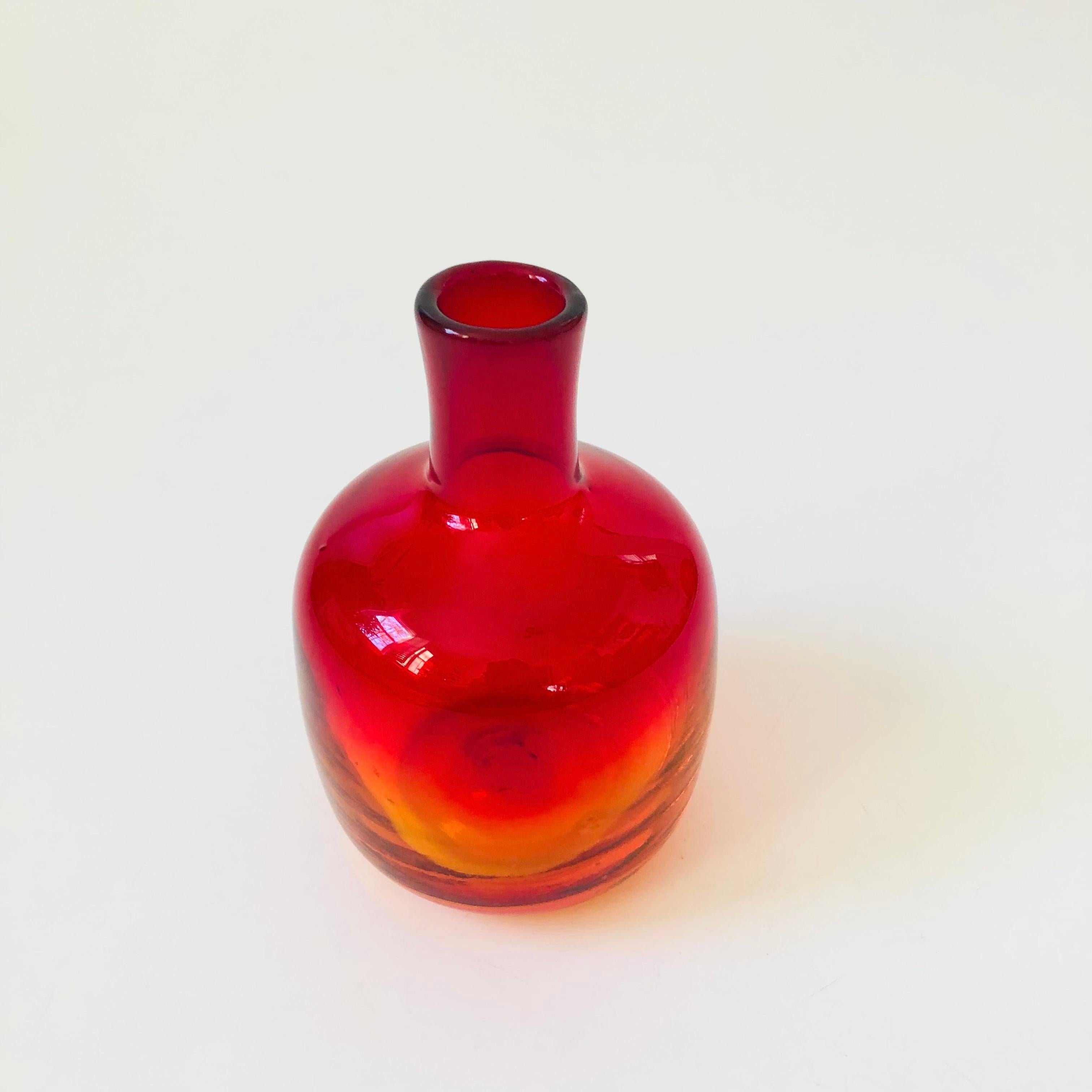 A vintage mid century bottle vase by Blenko in the tangerine color. Beautiful vibrant coloring to the glass that fades from orange to red.

