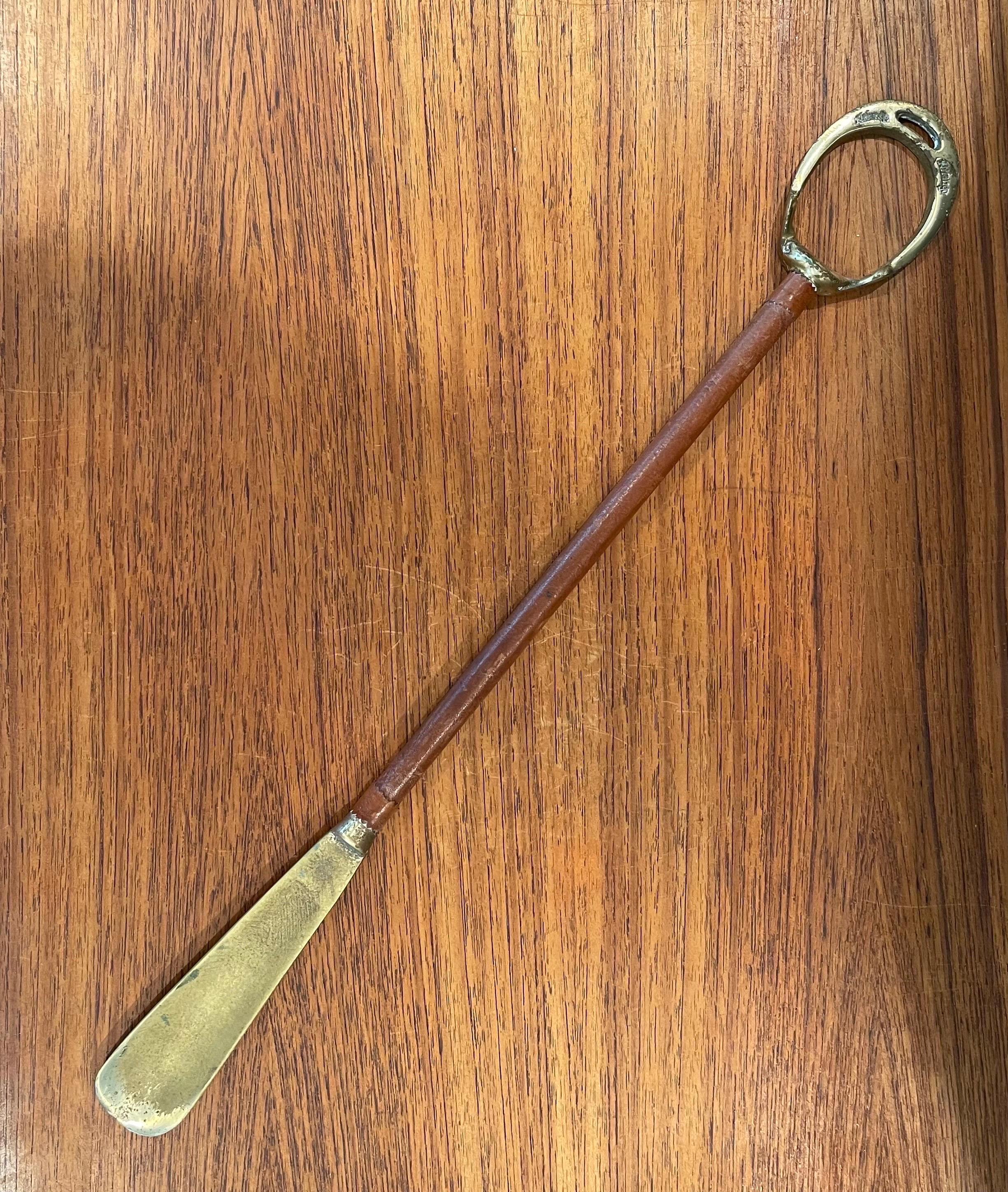 A very cool MCM brass and leather long shoehorn in the style of Jacques Adnet by Arfango, circa 1960s. The piece has a brass handle and Horn attached by saddle leather wrapped bar and measures 20