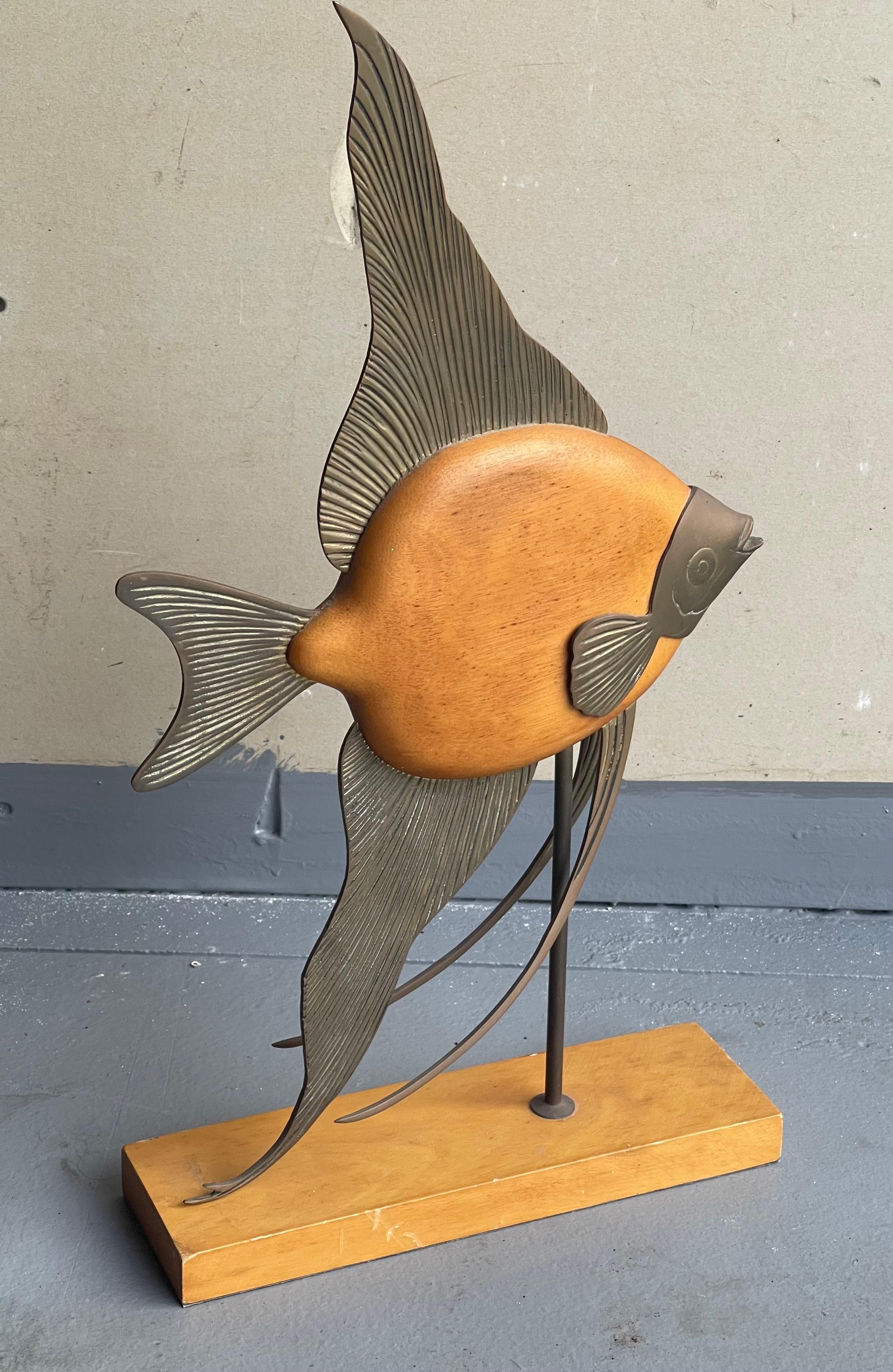 Vintage MCM large brass and light wood angel fish sculpture by Frederick Cooper, circa 1970s. The piece sits on a brass pole on a wood base and is in good vintage condition; it measures 11.75