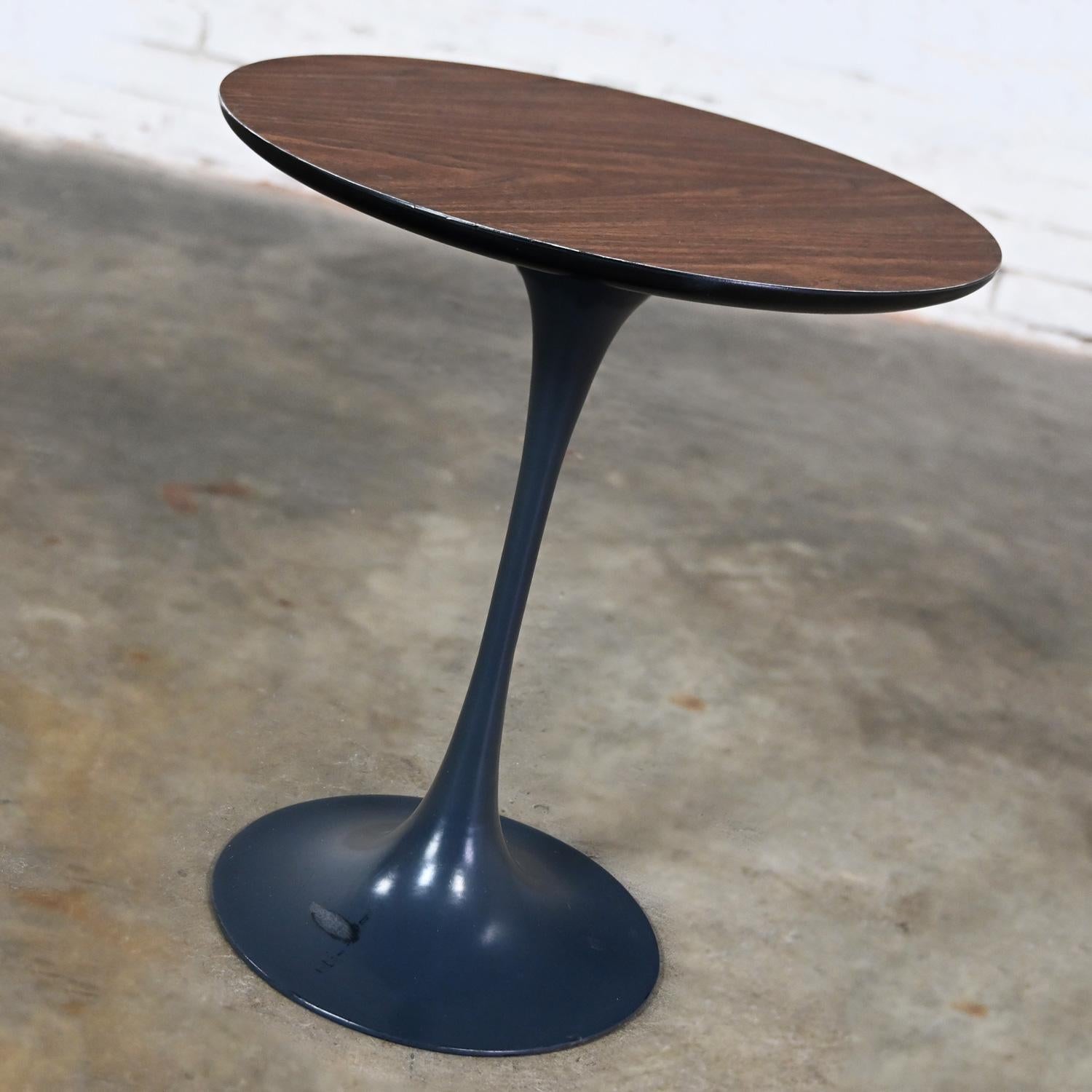 Handsome vintage MCM (a.k.a.) Mid-Century Modern Burke Division for Brunswick Tulip side table style of Eero Saarinen comprised of a wood grain laminate top with back beveled edge and a dark charcoal painted aluminum pedestal base. The Burke for