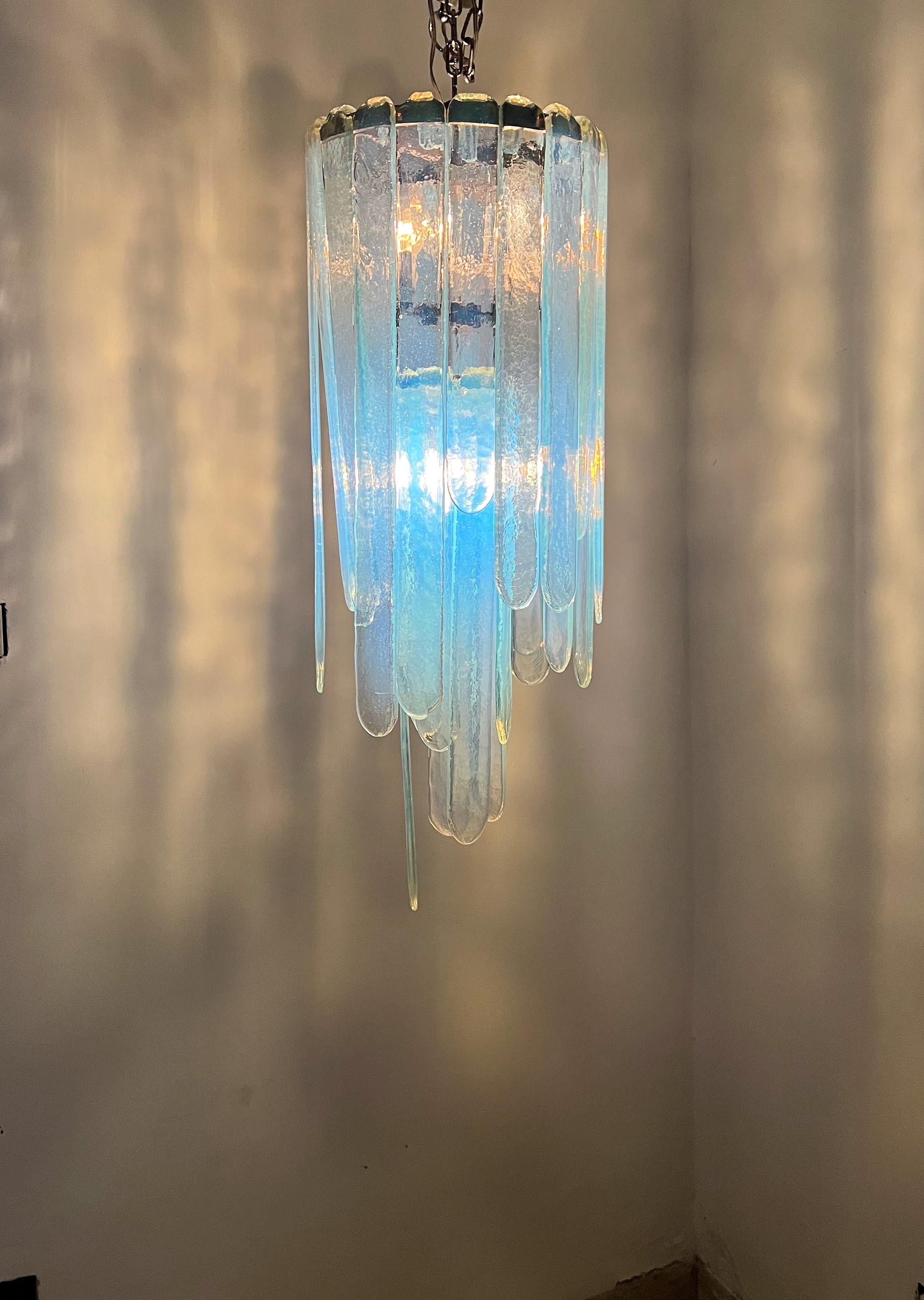 Mid-Century Modern chandelier by Carlo Nason for Mazzega in a blue opalescent hue, consisting of two stages of glass blades. 
It measures 85cm tall in its current arrangement, but can be made a little longer or shorter by simply exchanging the