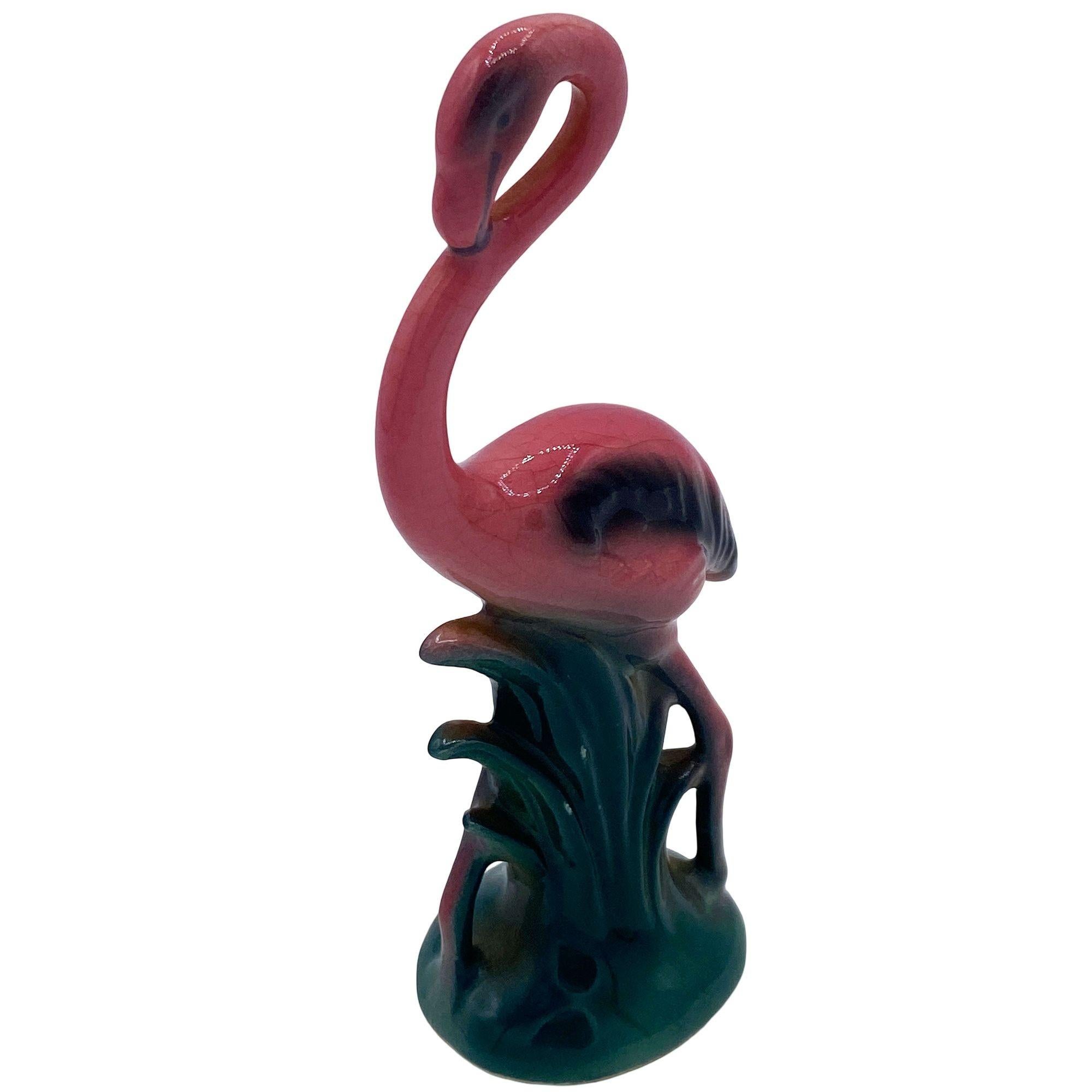 Mid-century pink and green ceramic flamingo statue set by Leftons. The set features two beautifully detailed pink flamingos in lush green leaves and grass with a pink color. Each comes with a gloss finish that highlights the rich pinks, greens, and