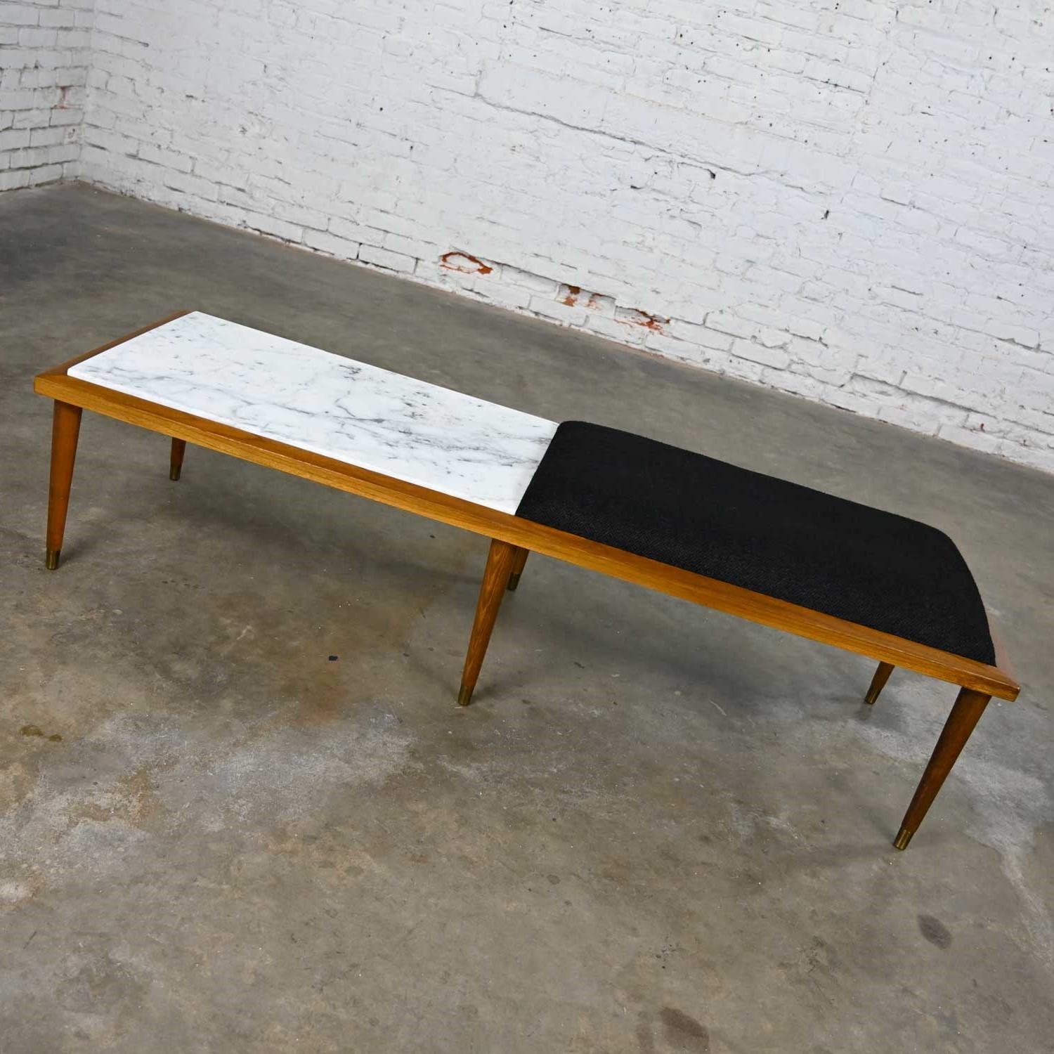 Handsome mid-century modern coffee table and bench combo half Italian Carrera marble & half black hopsacking fabric top with wood frame, tapered turned straight legs, & antiqued brass toned sabots. Beautiful condition, keeping in mind that this is