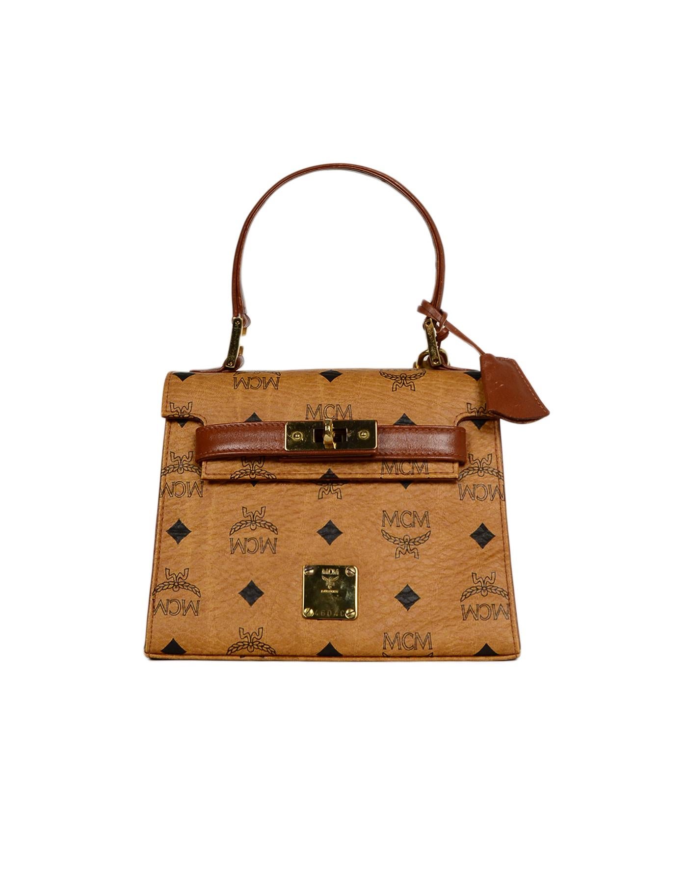 MCM Cognac Visetos Canvas Monogram Mini Kelly Style Bag w/ Clochette, Lock & Key

Made In: Germany
Color: Cognac and black
Hardware: Goldtone
Materials: Visetos canvas
Lining: Tan leather
Closure/Opening: Flap top with two leather arms and center