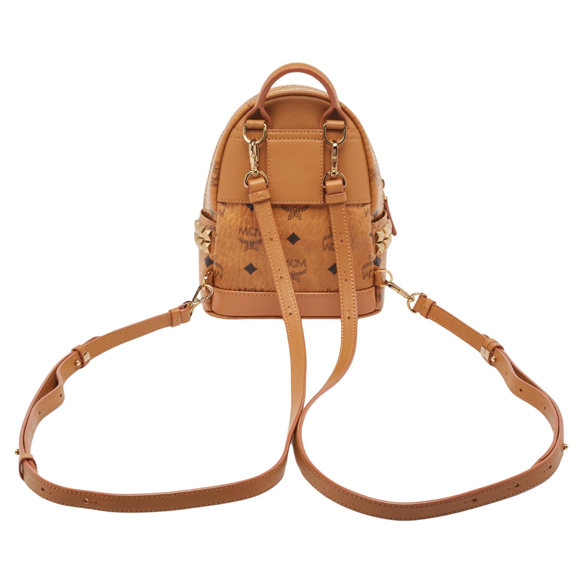 This MCM Stark-Bebe Boo backpack will come in handy for daily use or as a style statement. It is crafted from Visetos-coated canvas & leather and designed with gold-tone metal. It features a front zip pocket and two slip pockets on the