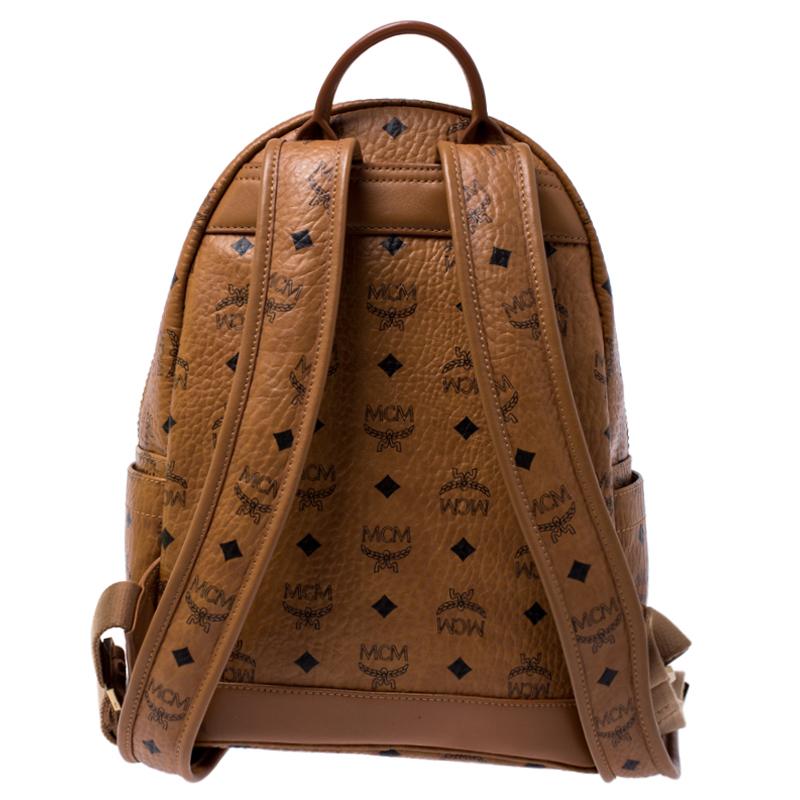 This stunning MCM backpack will come in handy for daily use or as a style statement. It is crafted from coated canvas and designed with studs, a front pocket and a spacious interior secured by a zipper. Two shoulder straps and a small top handle