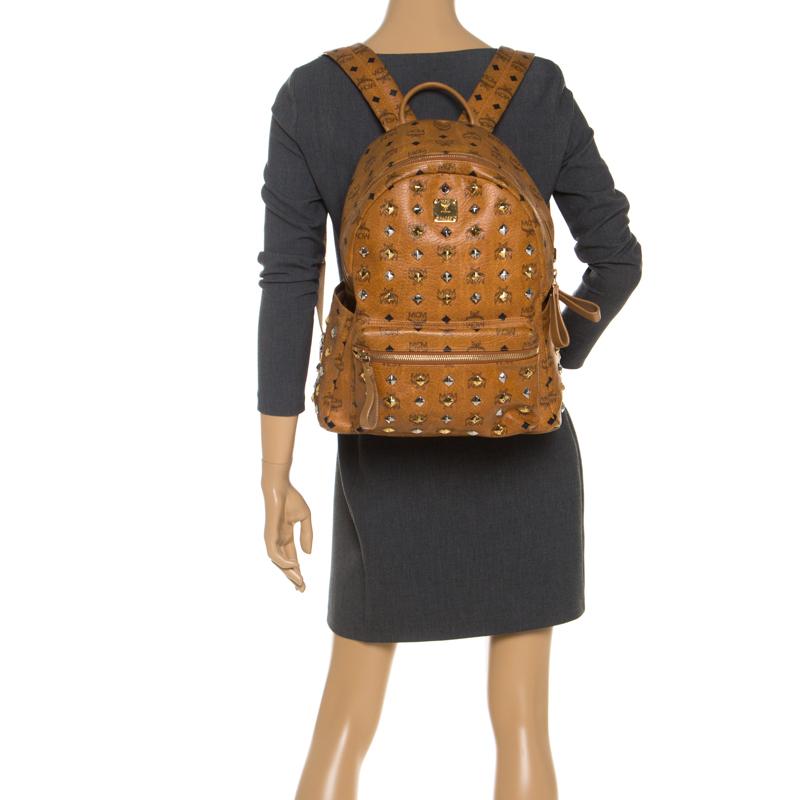 This stunning MCM backpack will come in handy for daily use or as a style statement. It is crafted from Cognac Visetos leather and designed with a front pocket and a spacious interior secured by a zipper. Two shoulder straps and a small top handle