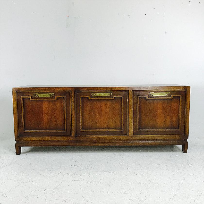 MCM credenza with brass hardware. The credenza is in good vintage condition and needs refinishing. Right side has a set of three drawers, the middle has a single drawer and an open area below, and the left side has an open space for storage.