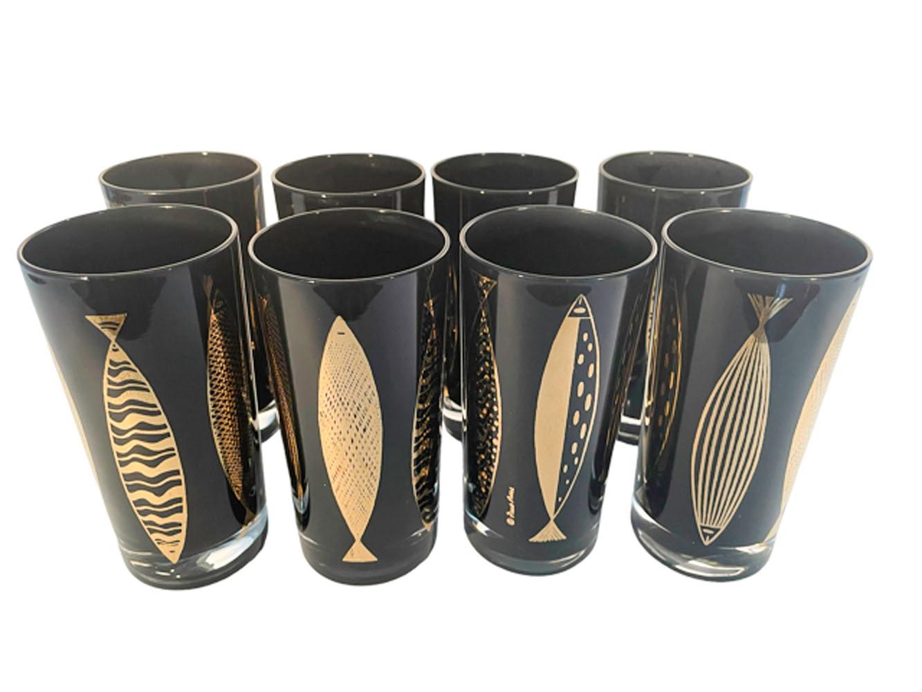 Eight Mid-Century Modern highball glasses designed by Fred Press, with 22k gold fish in different abstract patterns, vertically placed around each glass. The glasses are clear glass with the interiors frosted black creating a high gloss appearance