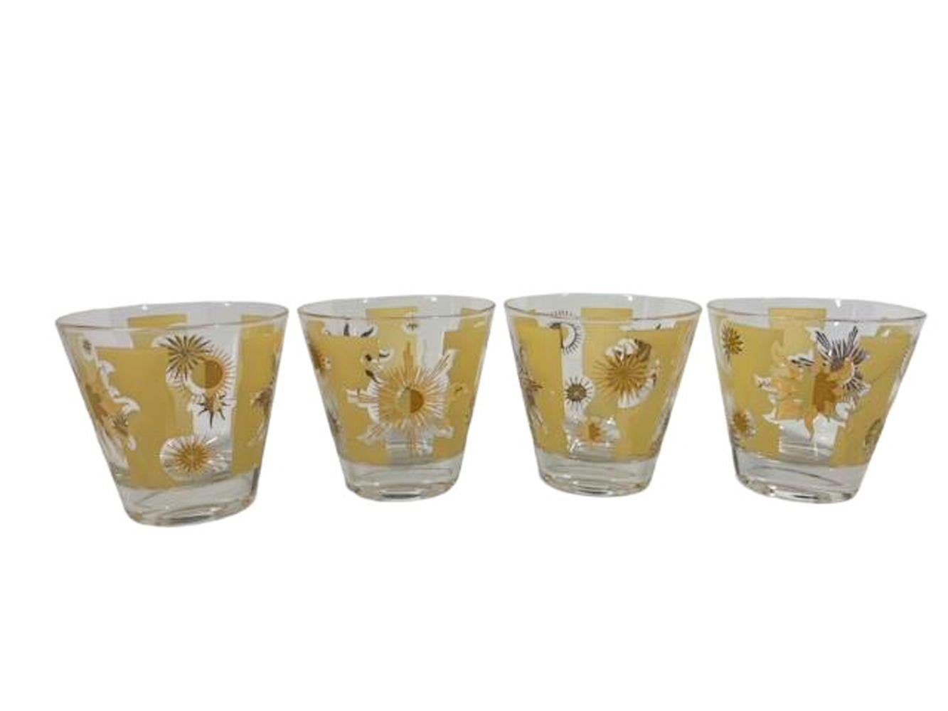 Set of four mid-century modern old fashioned glasses designed by Fred Press with panels of yellow enamel on clear glass with 22k gold starbursts randomly placed across the enameled and clear surfaces. 
