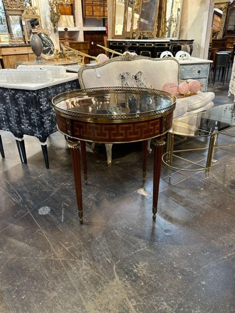 Handsome MCM French Empire style mahogany inlaid Bouilotte table. Featuring a pretty inlaid pattern, a mirrored top and brass gallery. Creates a very elegant look!!